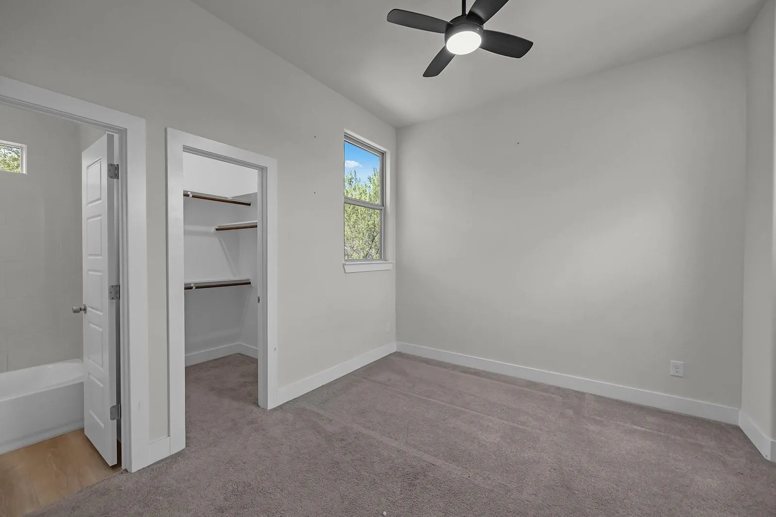 Recessed lighting, ceiling fan, plush carpeting, built-in closet shelving, and a window for natural light