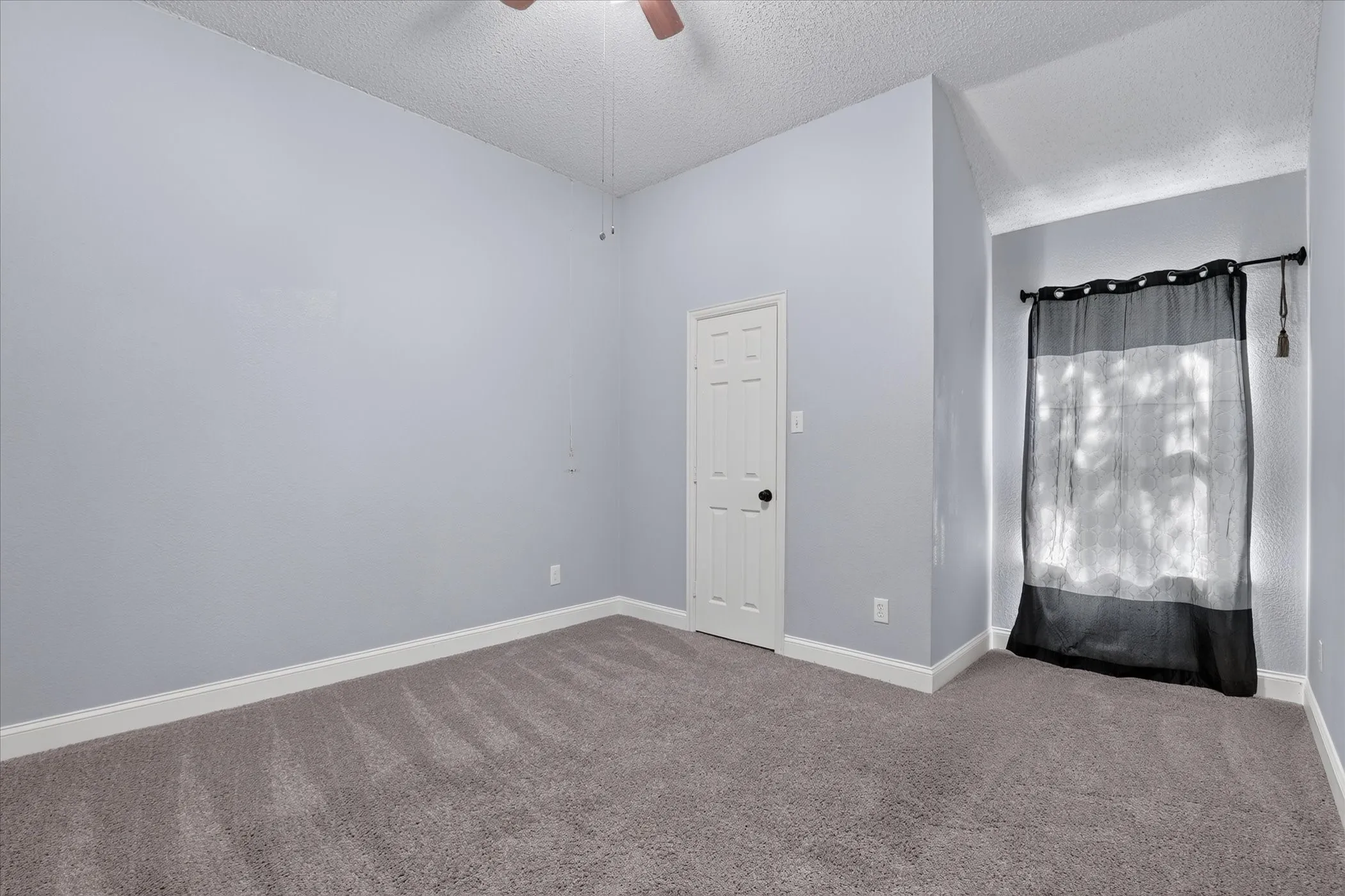 Carpeted flooring, vaulted ceiling, paneled door, ceiling fan