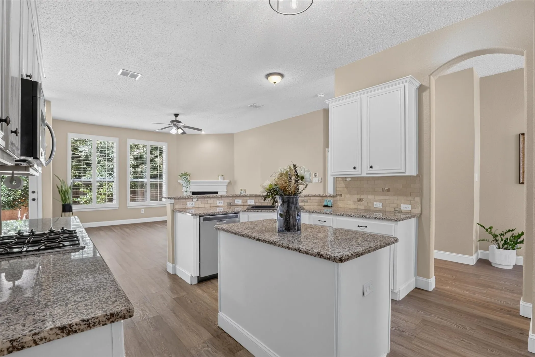 Kitchen featuring granite countertops, white cabinetry, a built-in microwave, and a gas cooktop