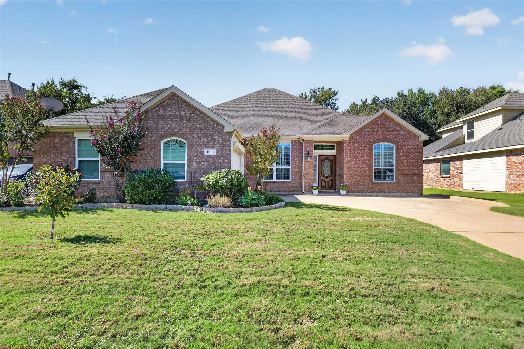 Brick exterior with arched window accents, a covered entry, and an attached garage