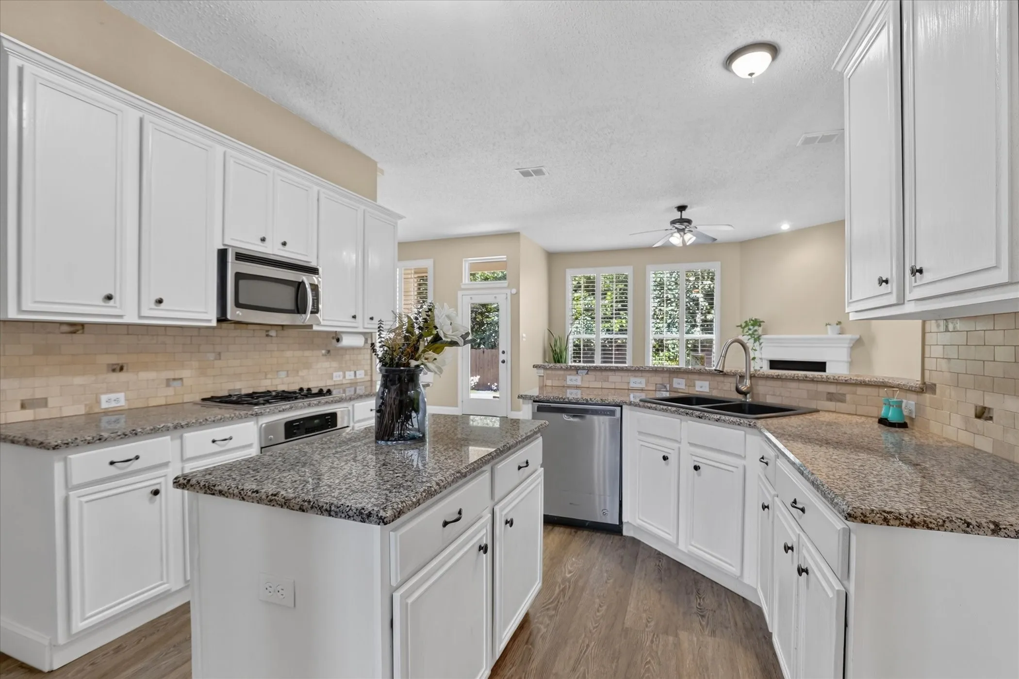 Kitchen featuring white cabinetry, granite countertops, a central island, stainless steel appliances, and wood-finish flooring