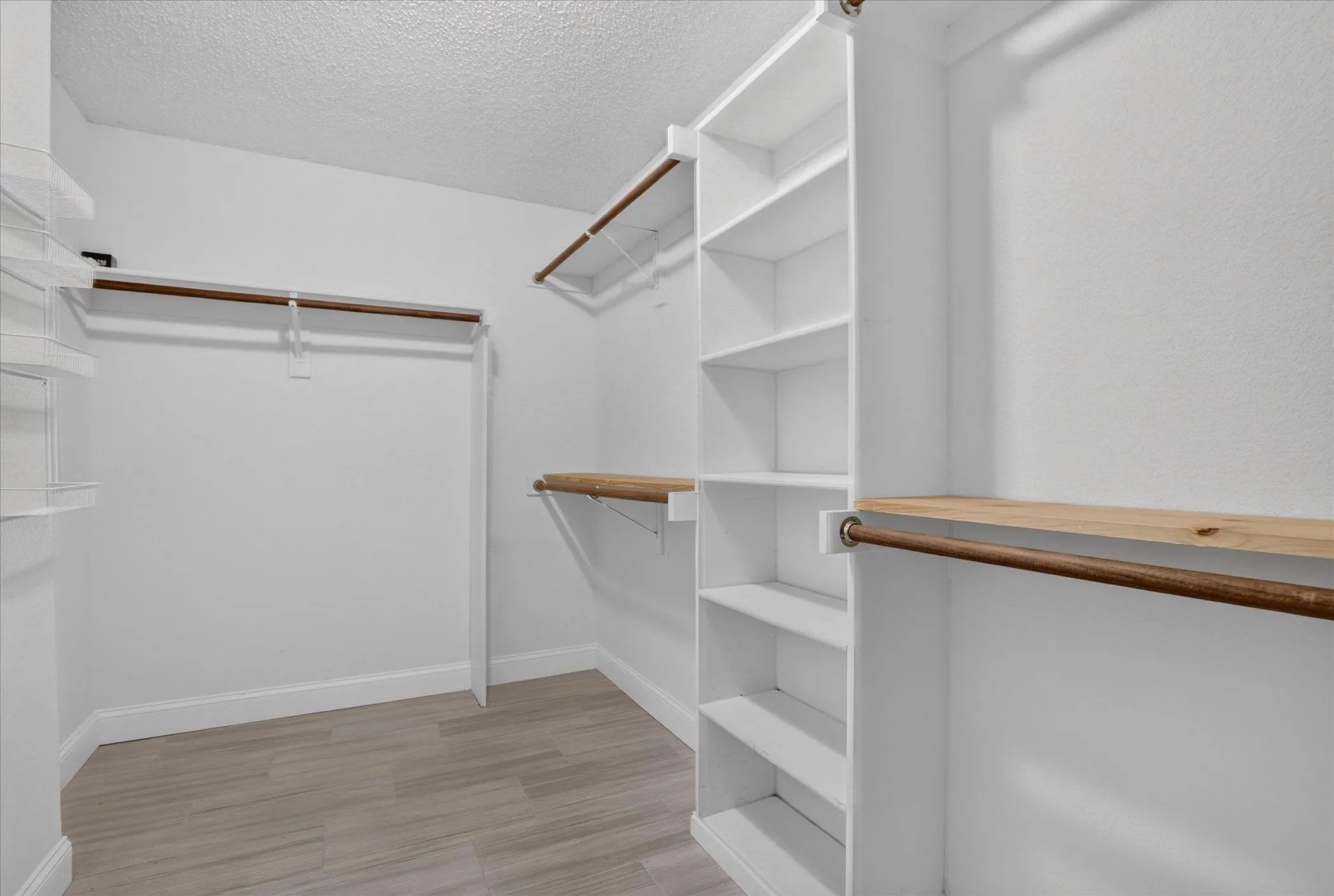 Custom closet system featuring built-in shelving, wood-finish rods, and wood-finish flooring