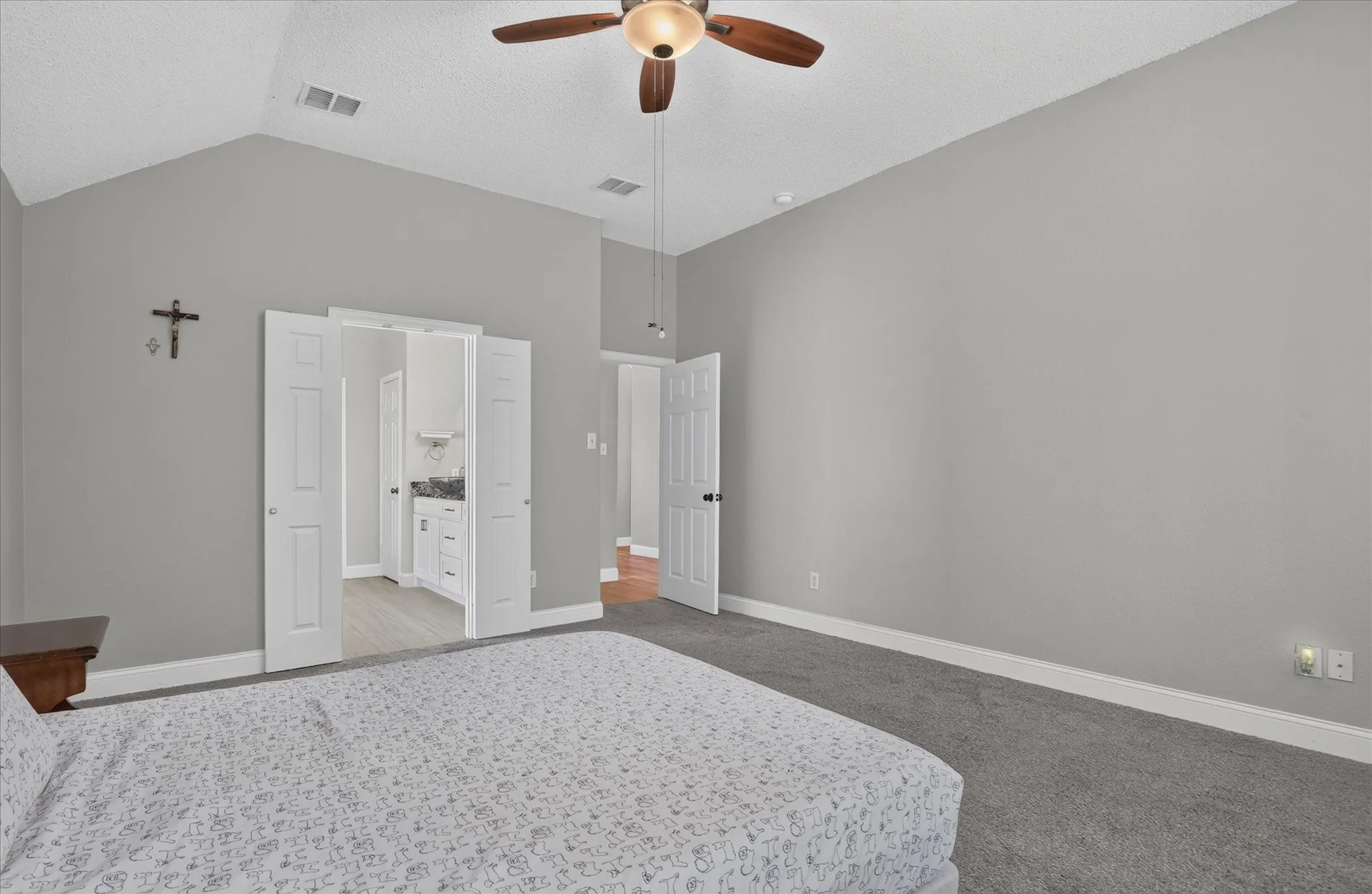 Vaulted ceiling with a ceiling fan, grey wall paint, and grey carpet flooring