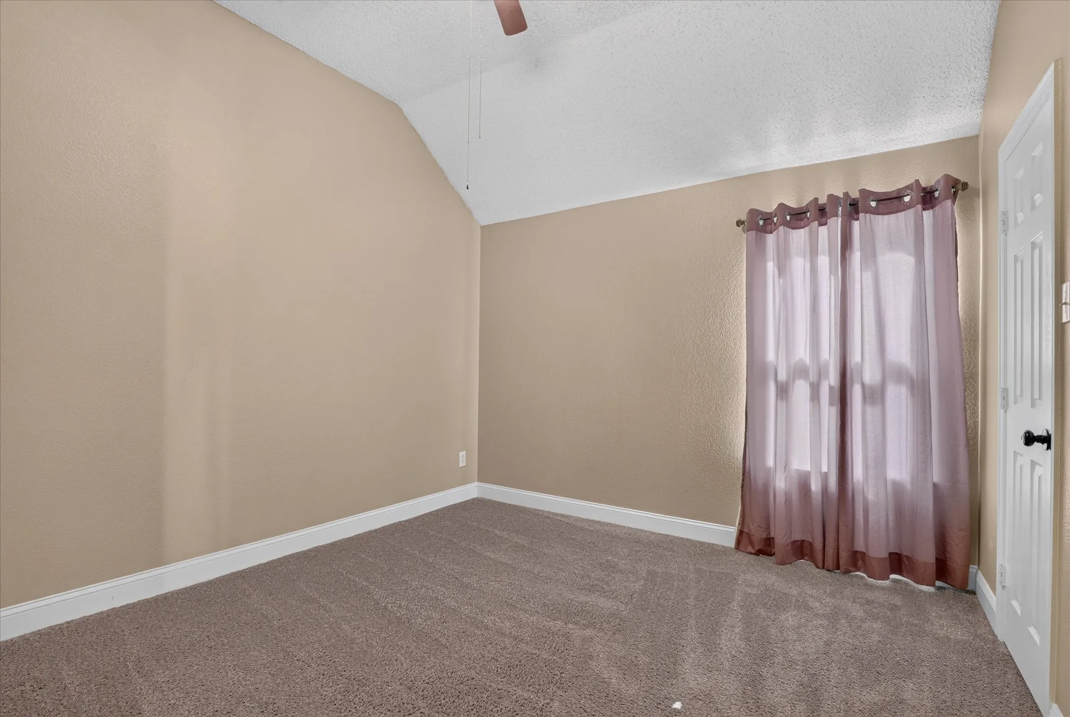 Vaulted ceiling, ceiling fan, neutral wall color, carpeted flooring, white trim