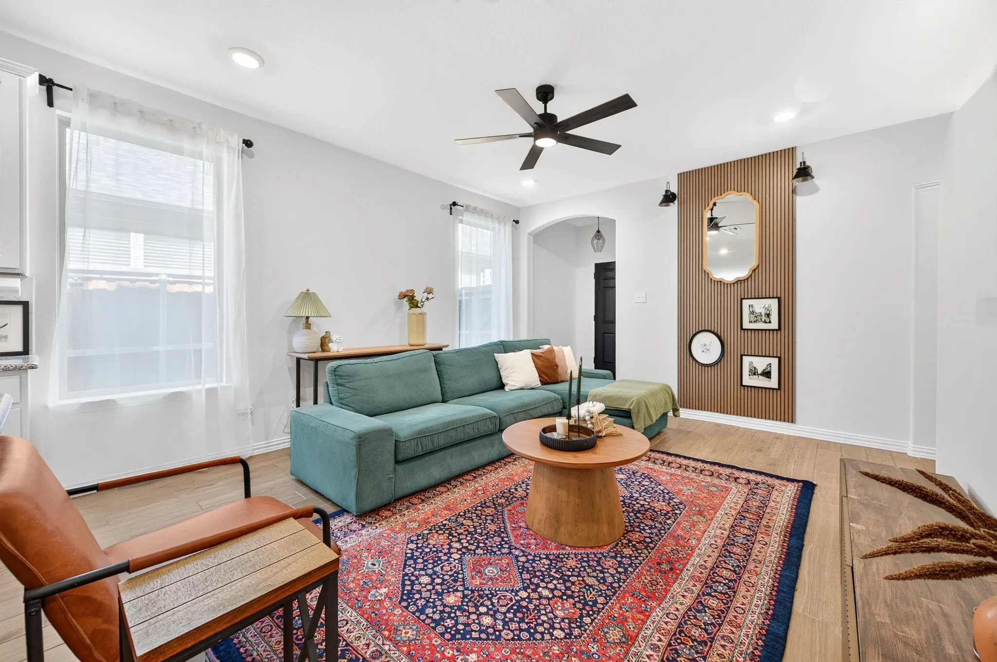 Recessed lighting, wood-finish flooring, a ceiling fan, arched doorway, and feature wall with sconces