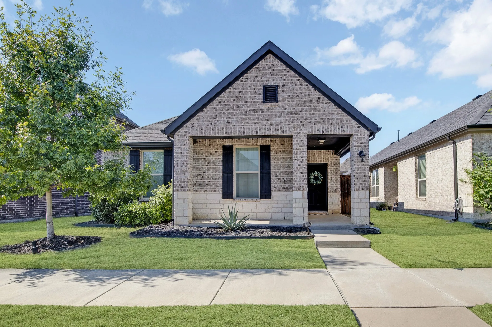 Charming brick residence featuring a gabled roofline and covered front porch with stone accents