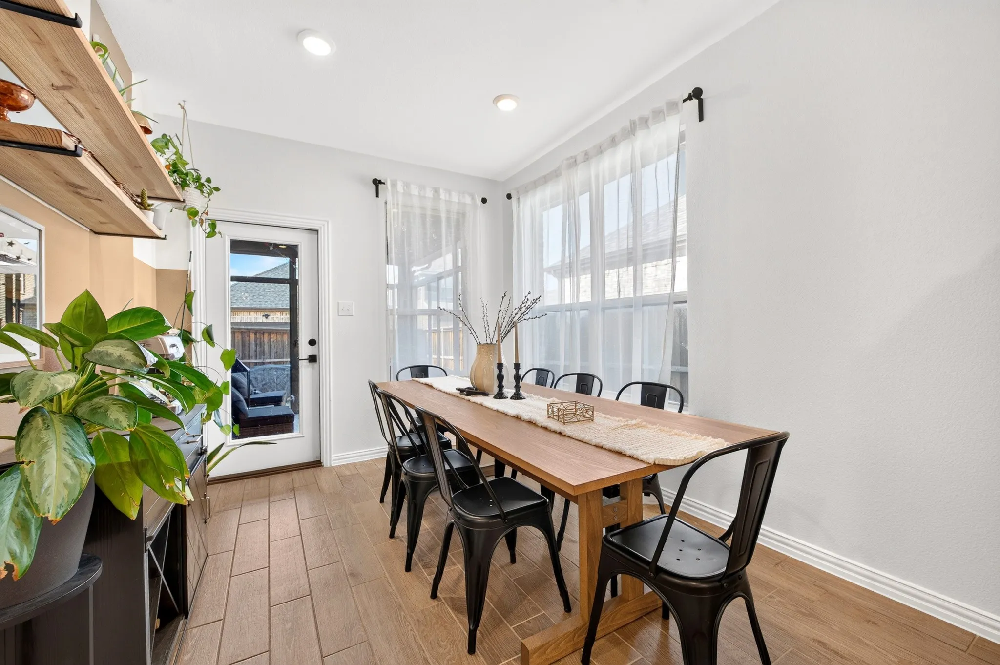 Recessed lighting, wood-finish flooring, multiple windows with sheer treatments, exterior access door with glass panel, and built-in wall shelving