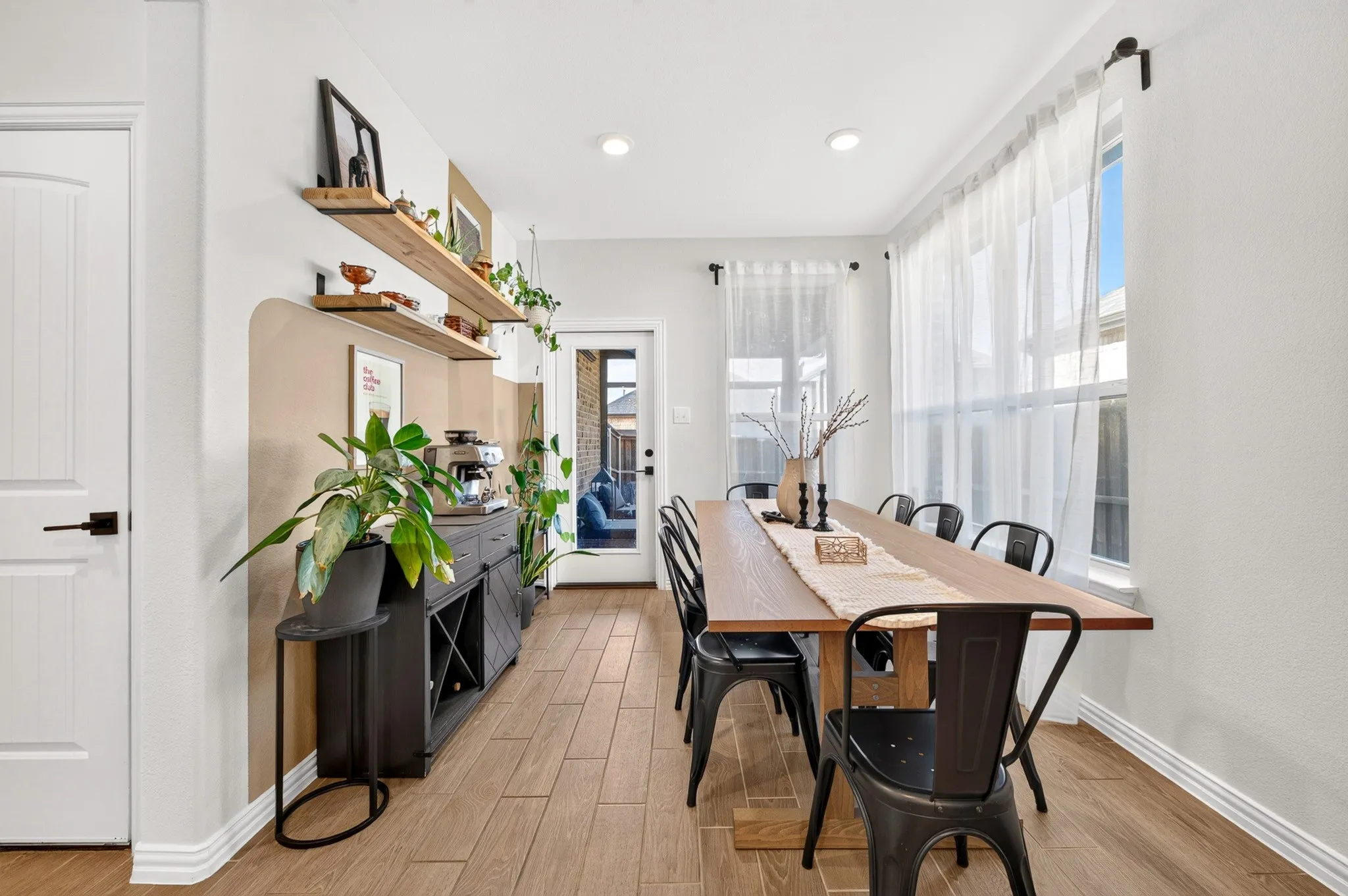 Bright dining space featuring wood-finish flooring, a custom dining table with seating for six, and black bentwood chairs