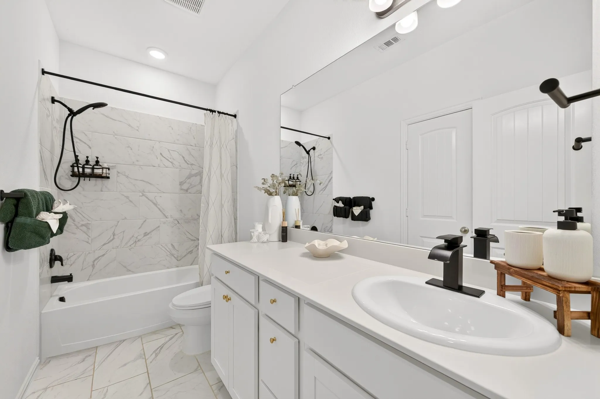 Spa-inspired primary bathroom featuring a dual-sink vanity with white cabinetry, quartz countertop, and matte black faucetry