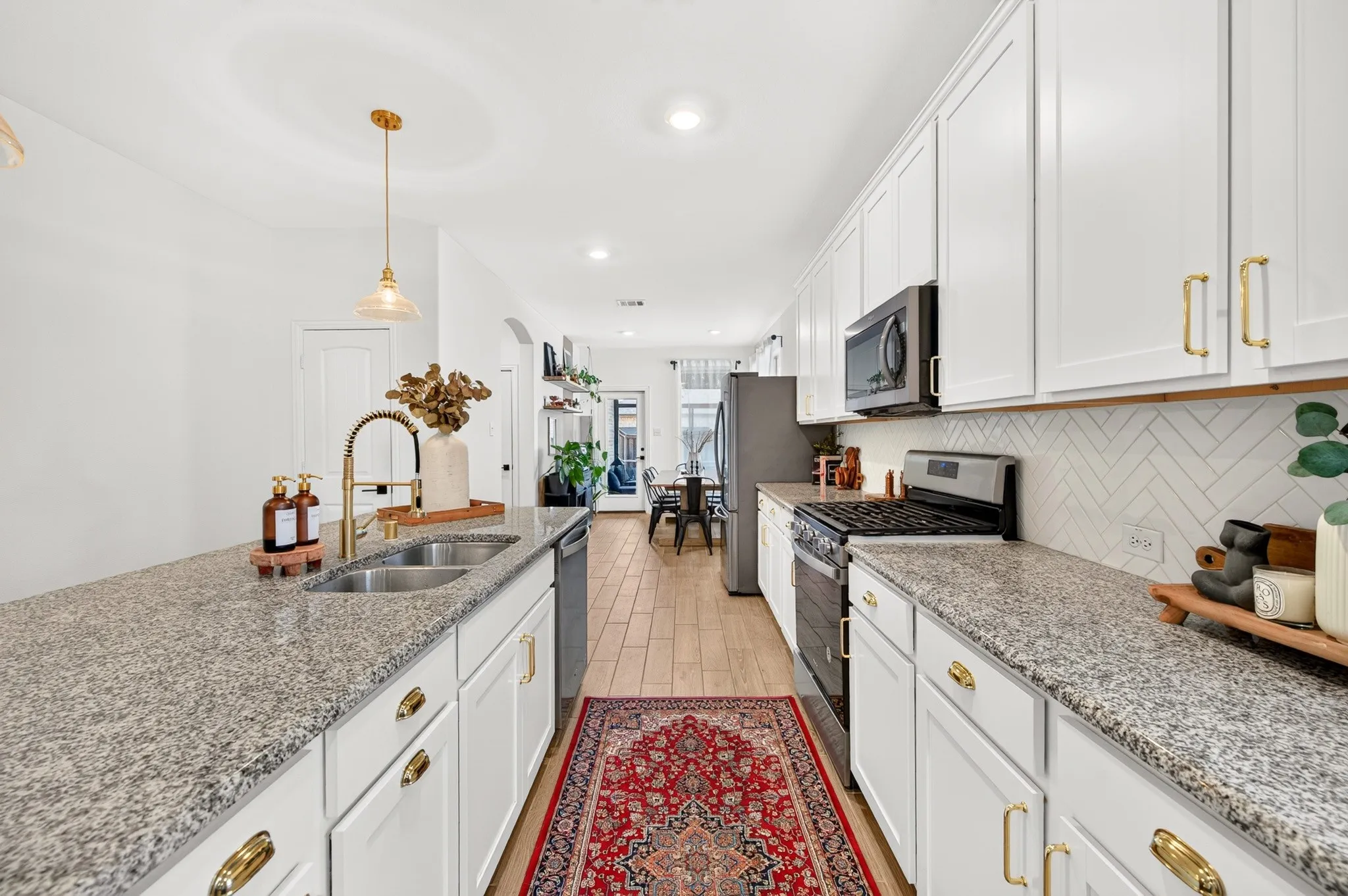 Kitchen with white cabinetry, granite countertops, stainless steel appliances, and a herringbone tile backsplash