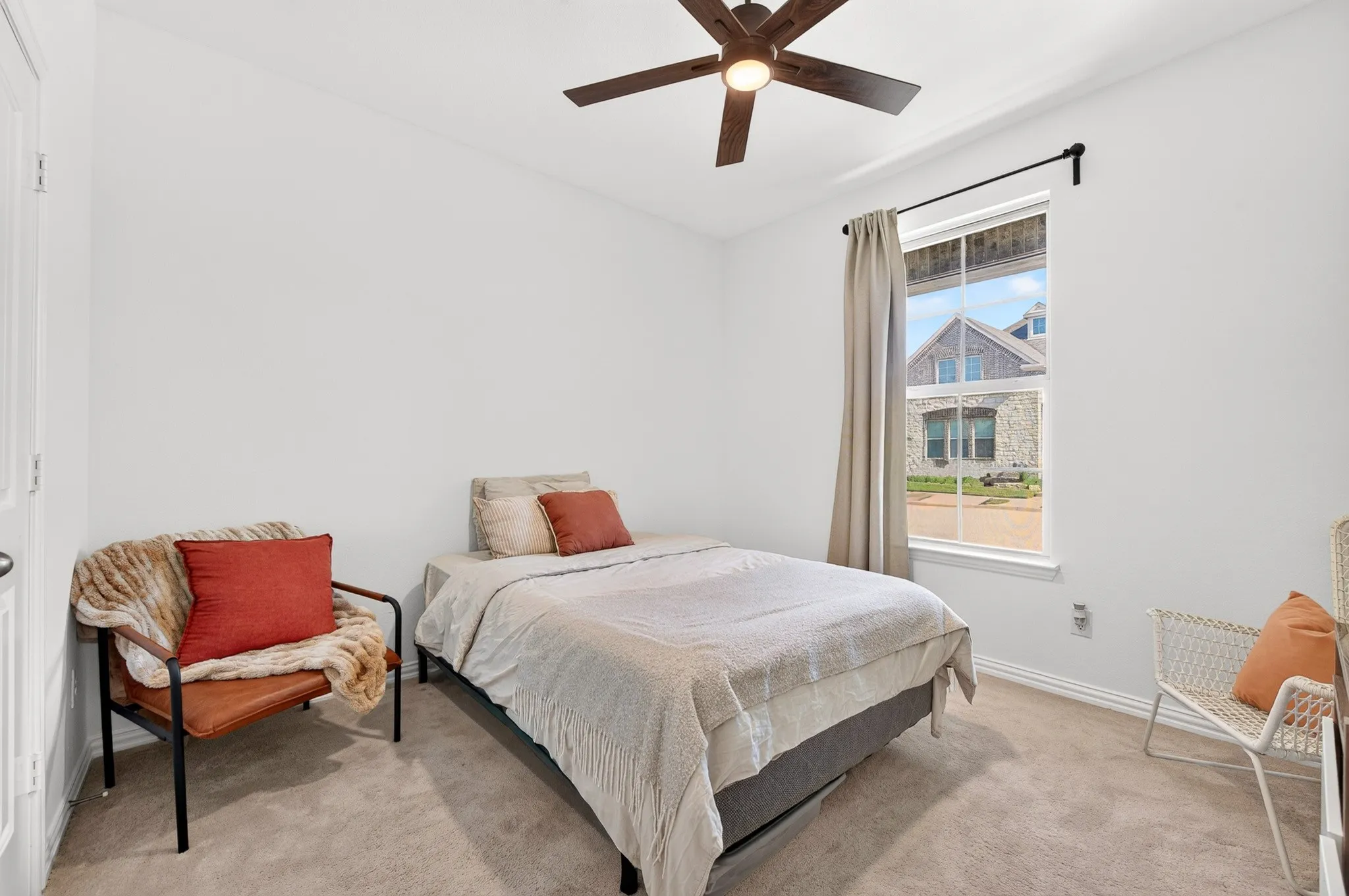 Neutral wall color, carpeted flooring, a ceiling fan with integrated lighting, and a single window with a dark-finished rod