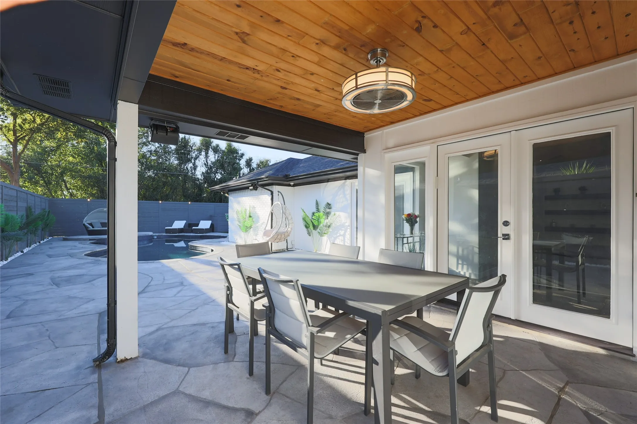 Covered patio with a wood-finish ceiling, mounted ceiling fan, and French doors