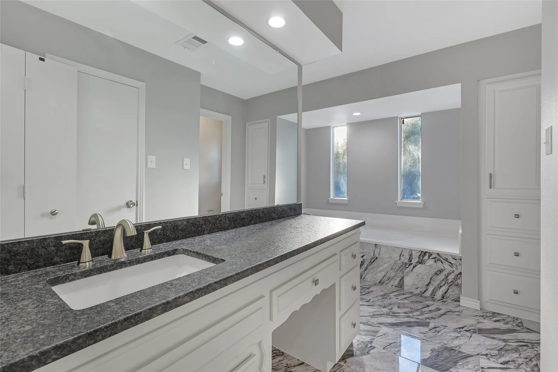 Vanity with dark speckled countertop, undermount sink, and brushed nickel faucet