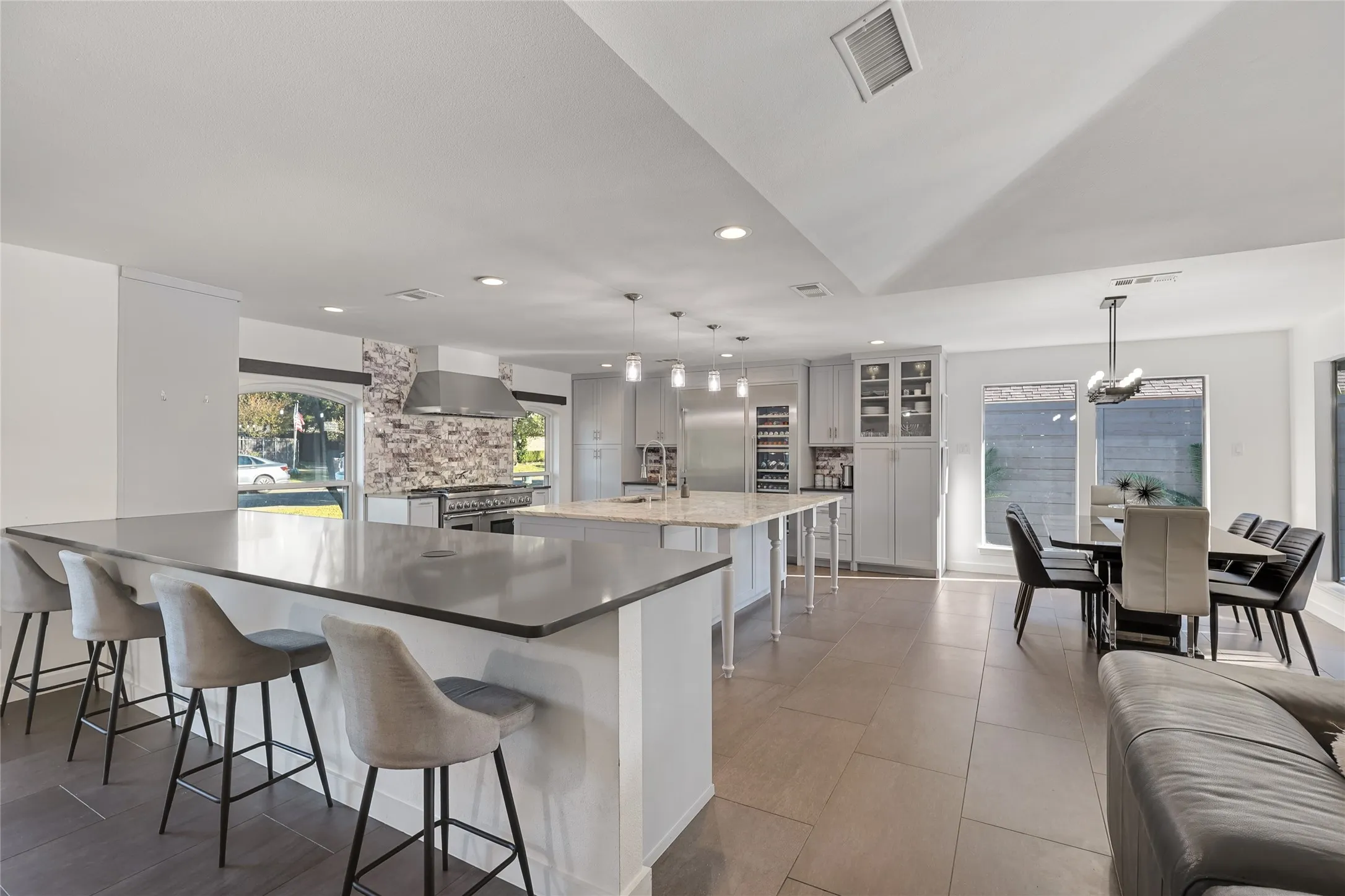 Spacious open-concept living area featuring an expansive kitchen island with seating, a secondary kitchen island, a dining area, built-in cabinetry, and tile flooring