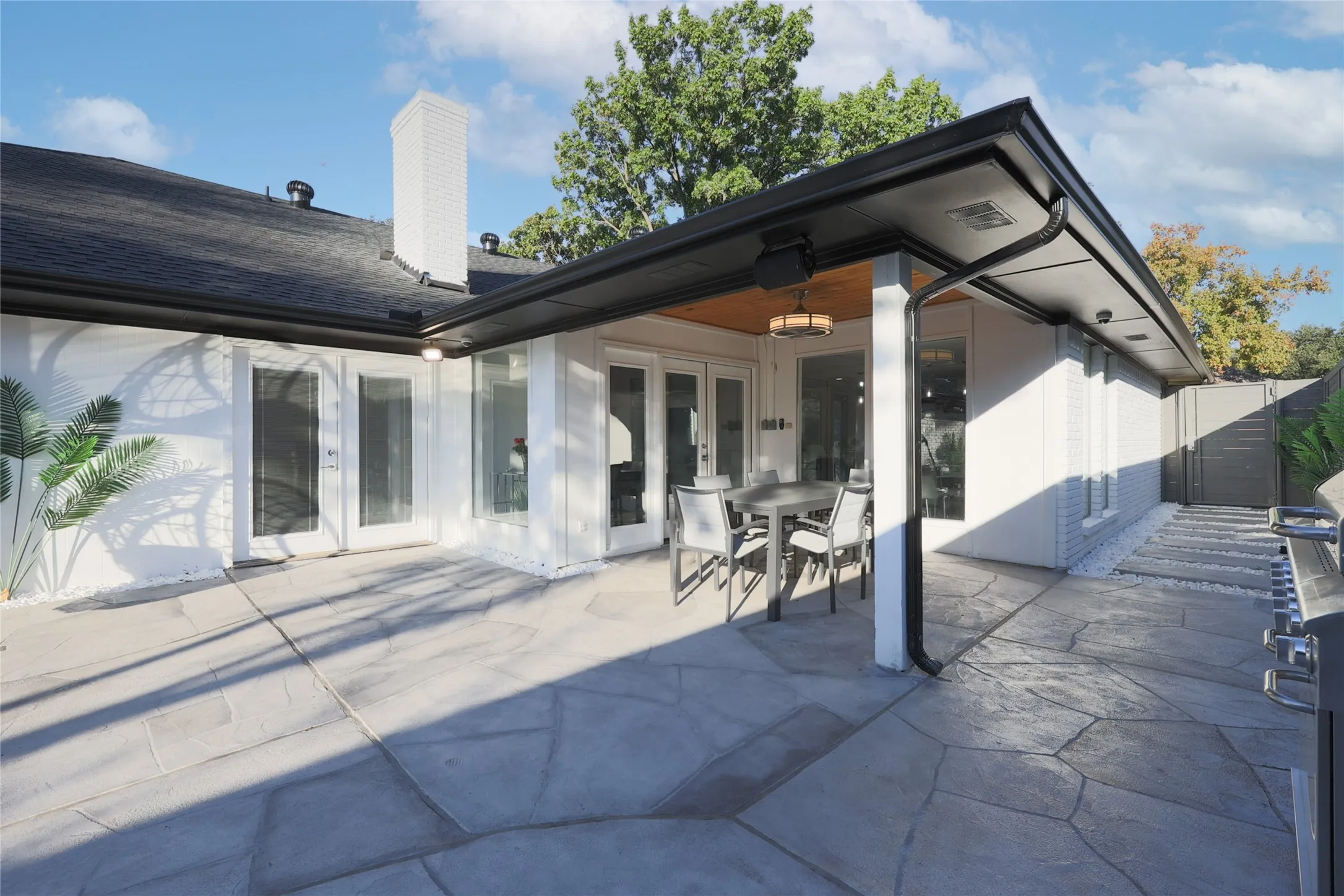 Expansive patio featuring stamped concrete, a covered section with wood-finish ceiling, and multiple access points to the interior