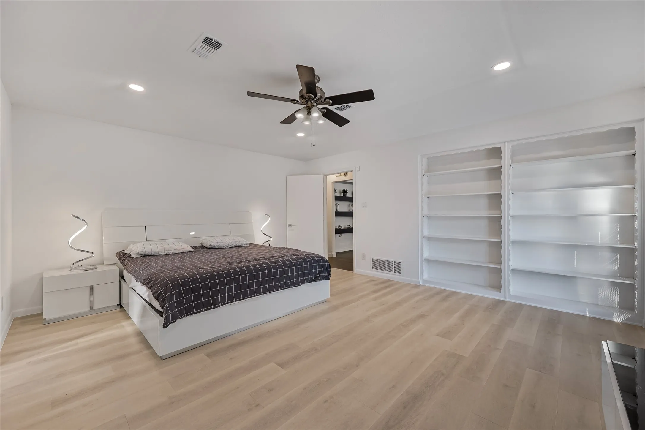 Recessed lighting, wood-finish flooring, ceiling fan with light fixture, built-in shelving, and white walls