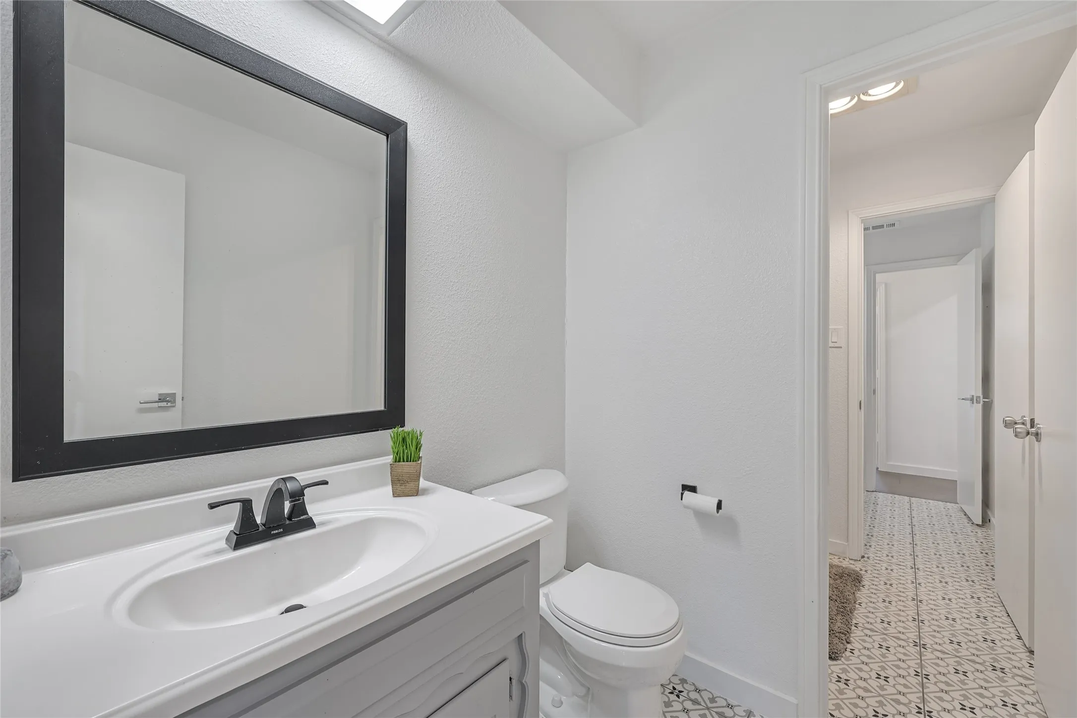 Bathroom featuring a single vanity with an integrated sink, a dark framed mirror, and a black faucet
