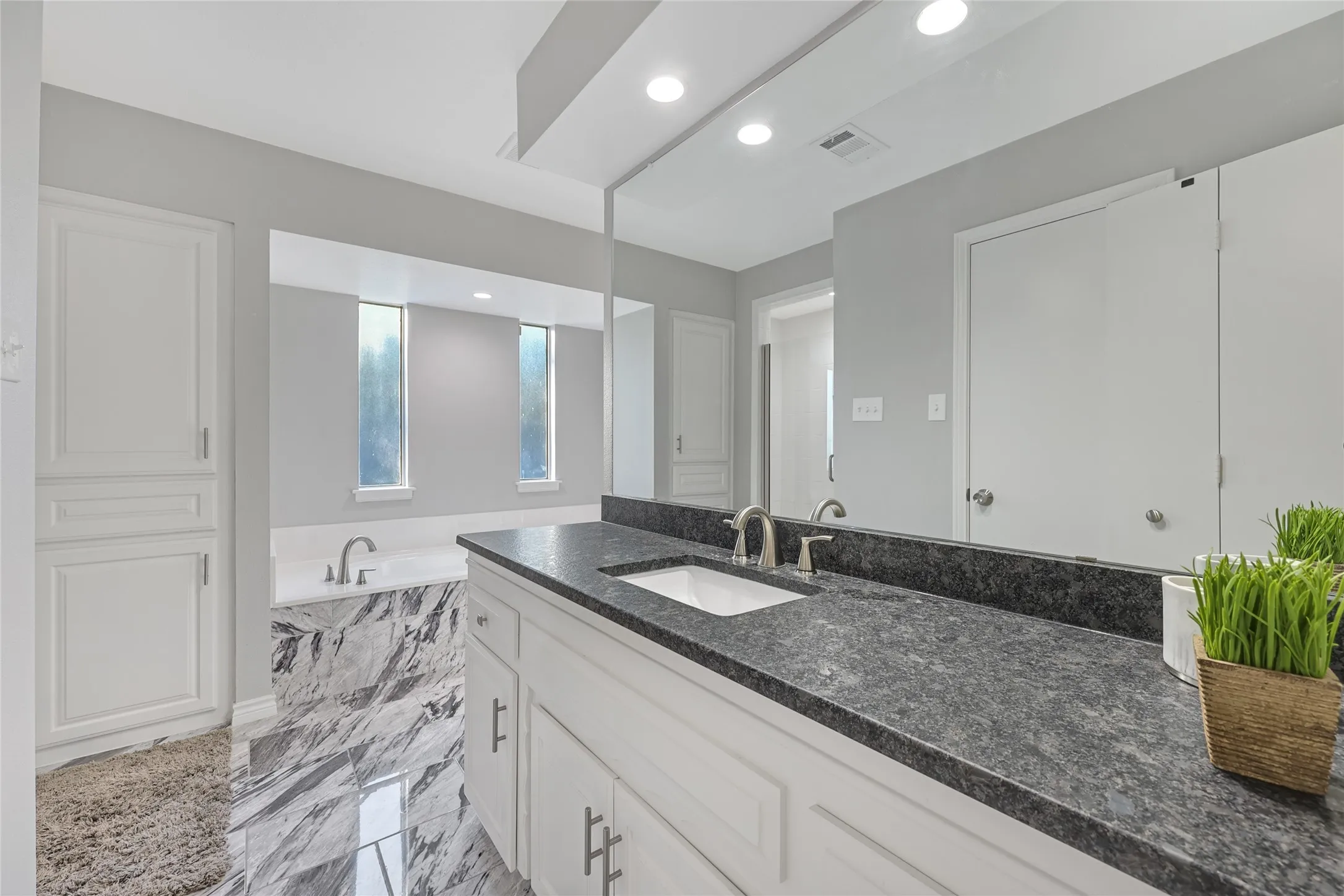 Dual vanity with dark stone countertops, undermount sinks, and brushed nickel fixtures