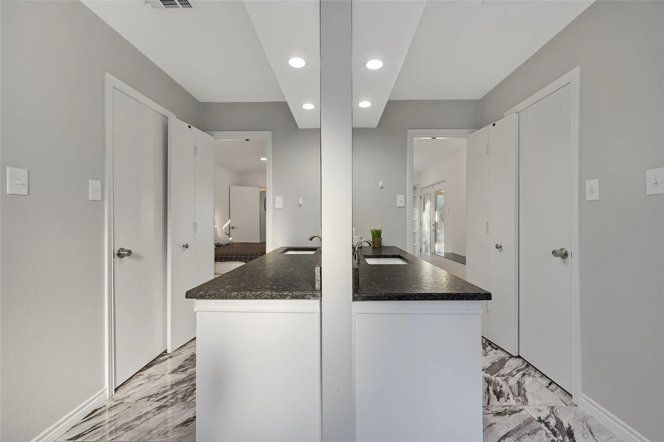 Dual vanity with dark stone countertops and integrated sinks