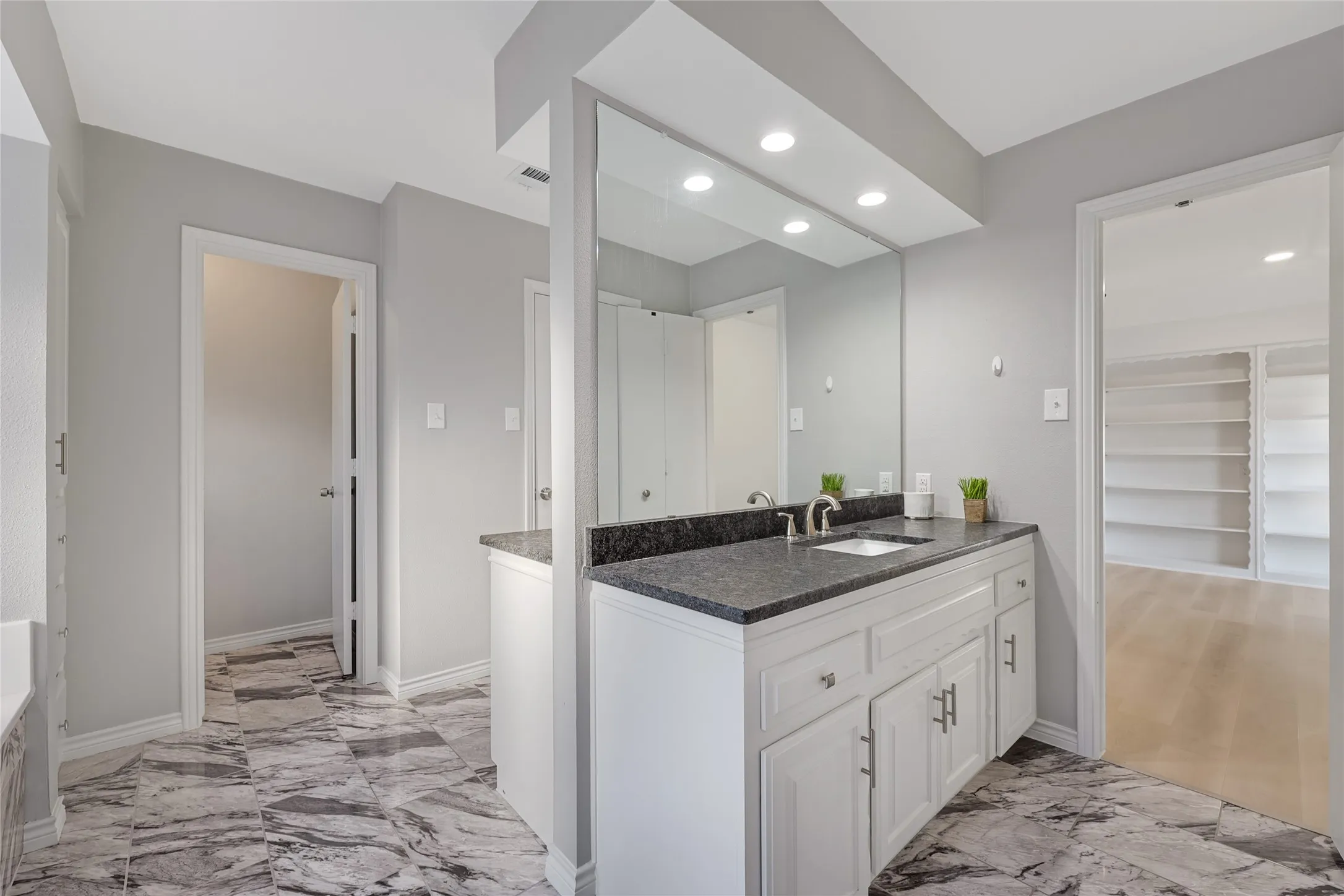 White vanity with a dark countertop and integrated sink