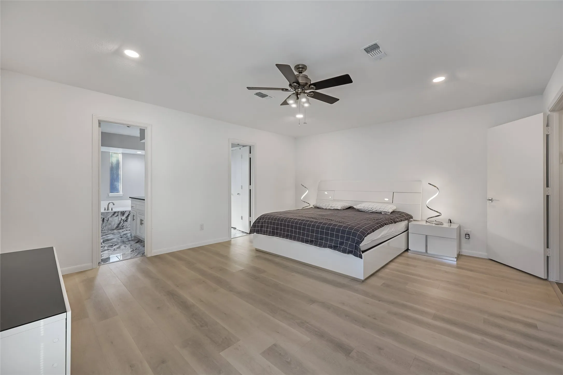 Spacious room with wood-finish flooring, recessed ceiling lighting, and a ceiling fan with integrated lighting