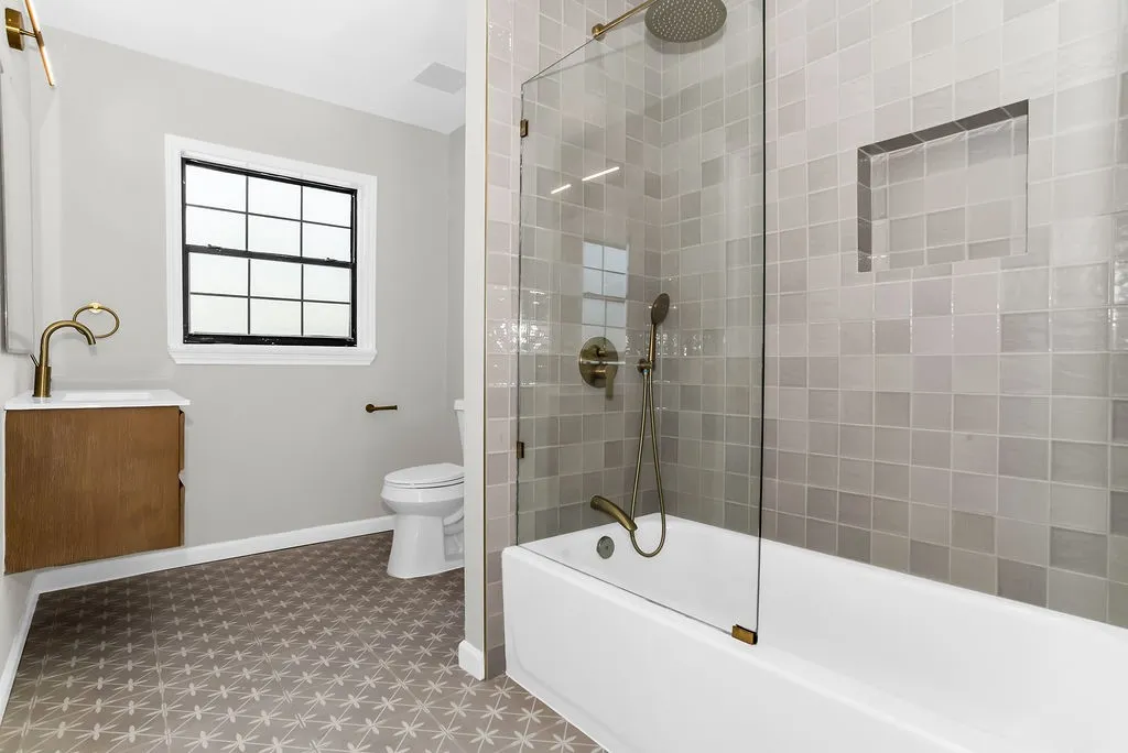 Upstairs bathroom with patterned tile floor and glass-panel shower