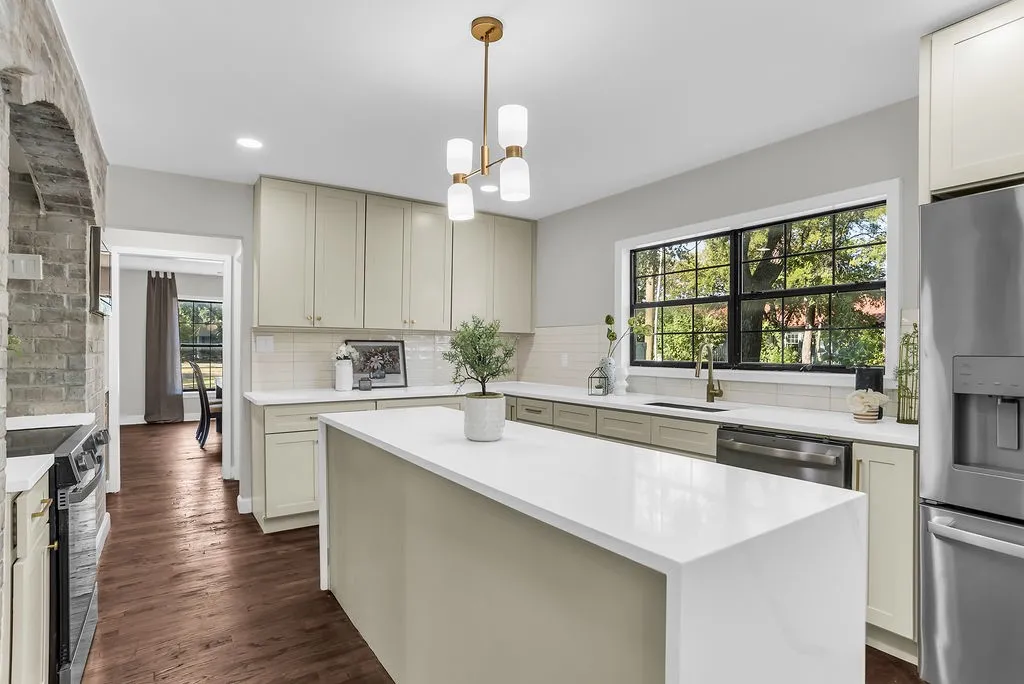 Kitchen with waterfall quartz island, shaker cabinetry and stainless appliances