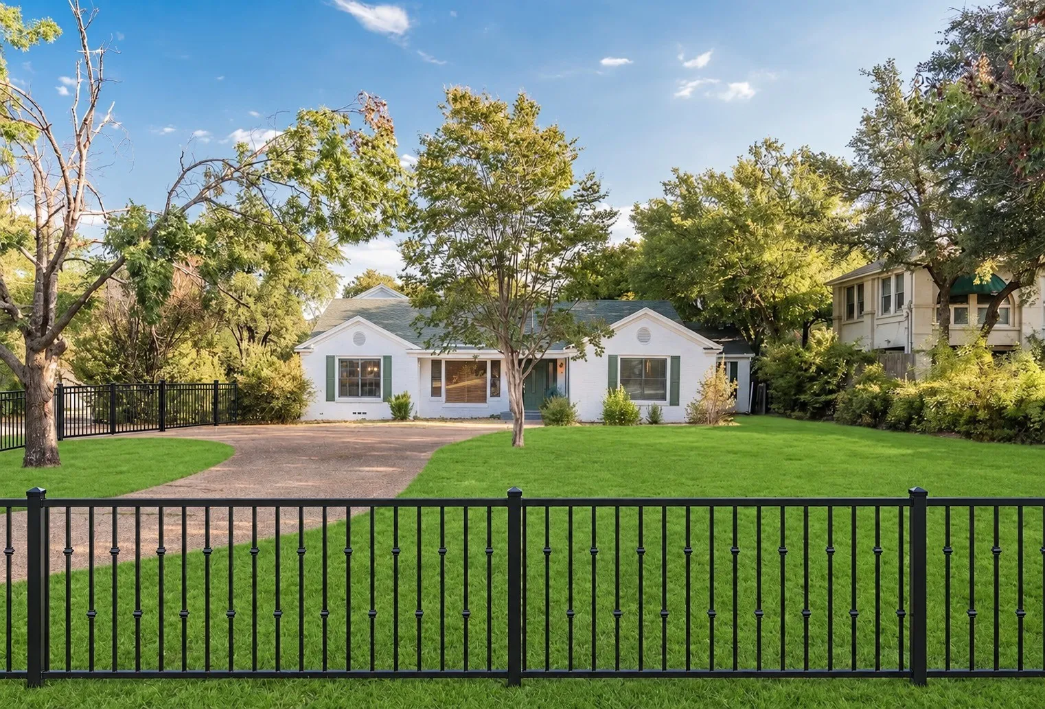 Front exterior with the new black metal fence along the front lawn and circular drive