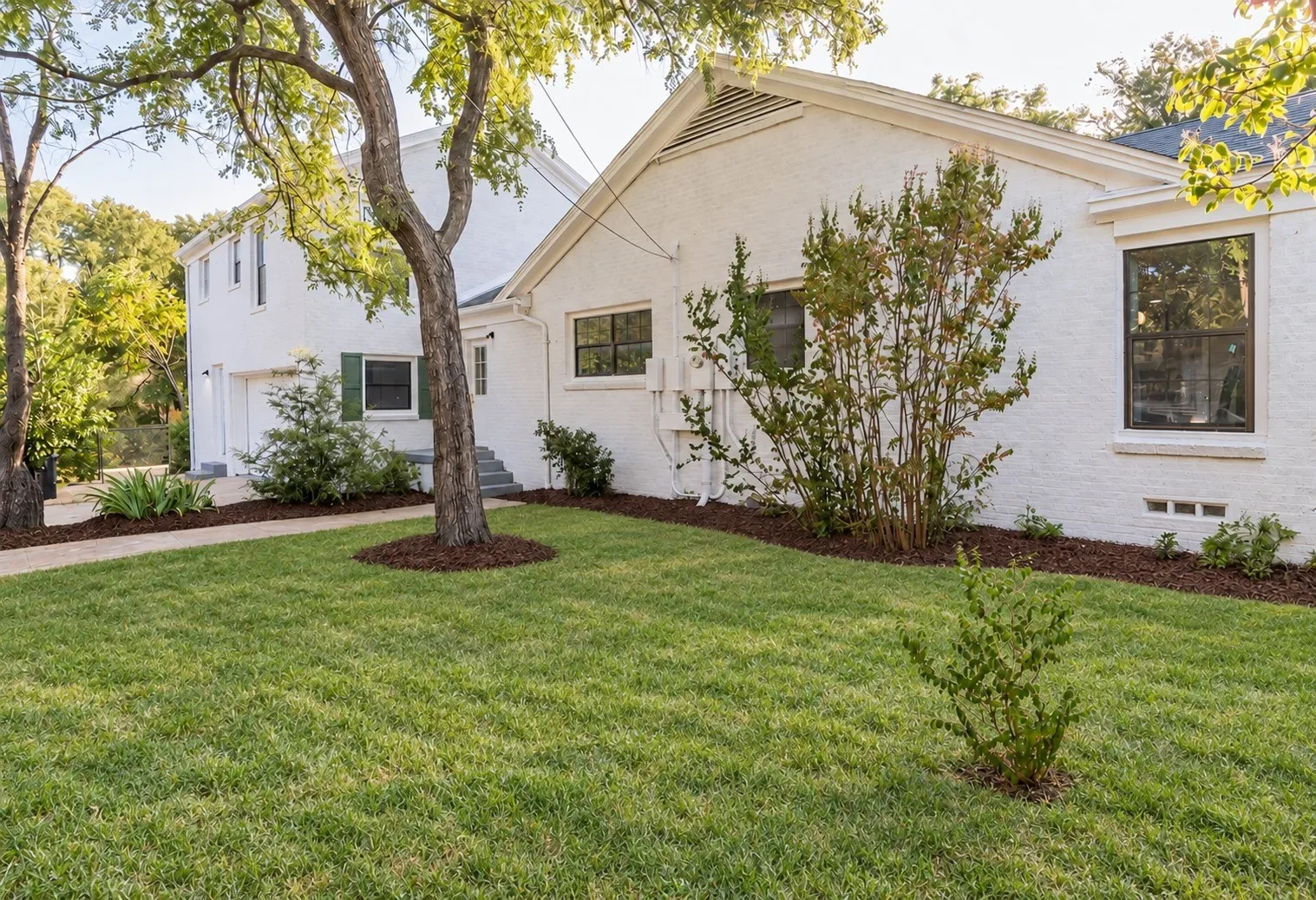 Side yard with green lawn and fresh mulch along the house