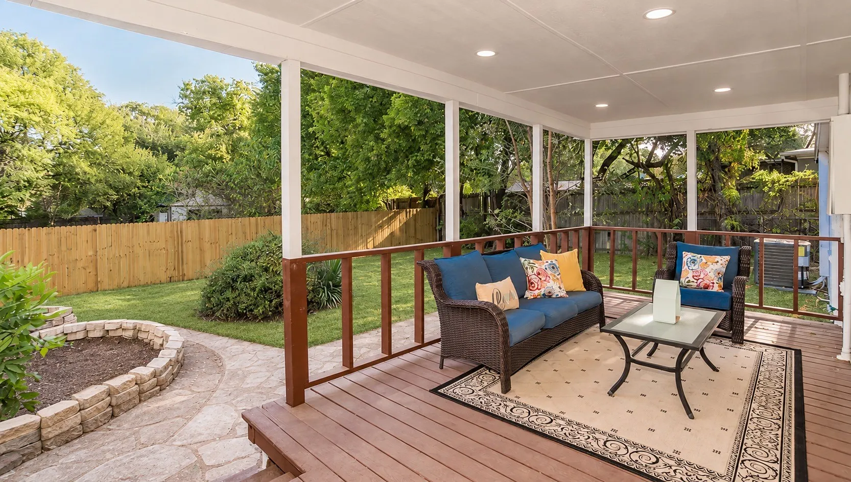 Covered back patio with recessed lighting overlooking the fenced, tree-lined backyard
