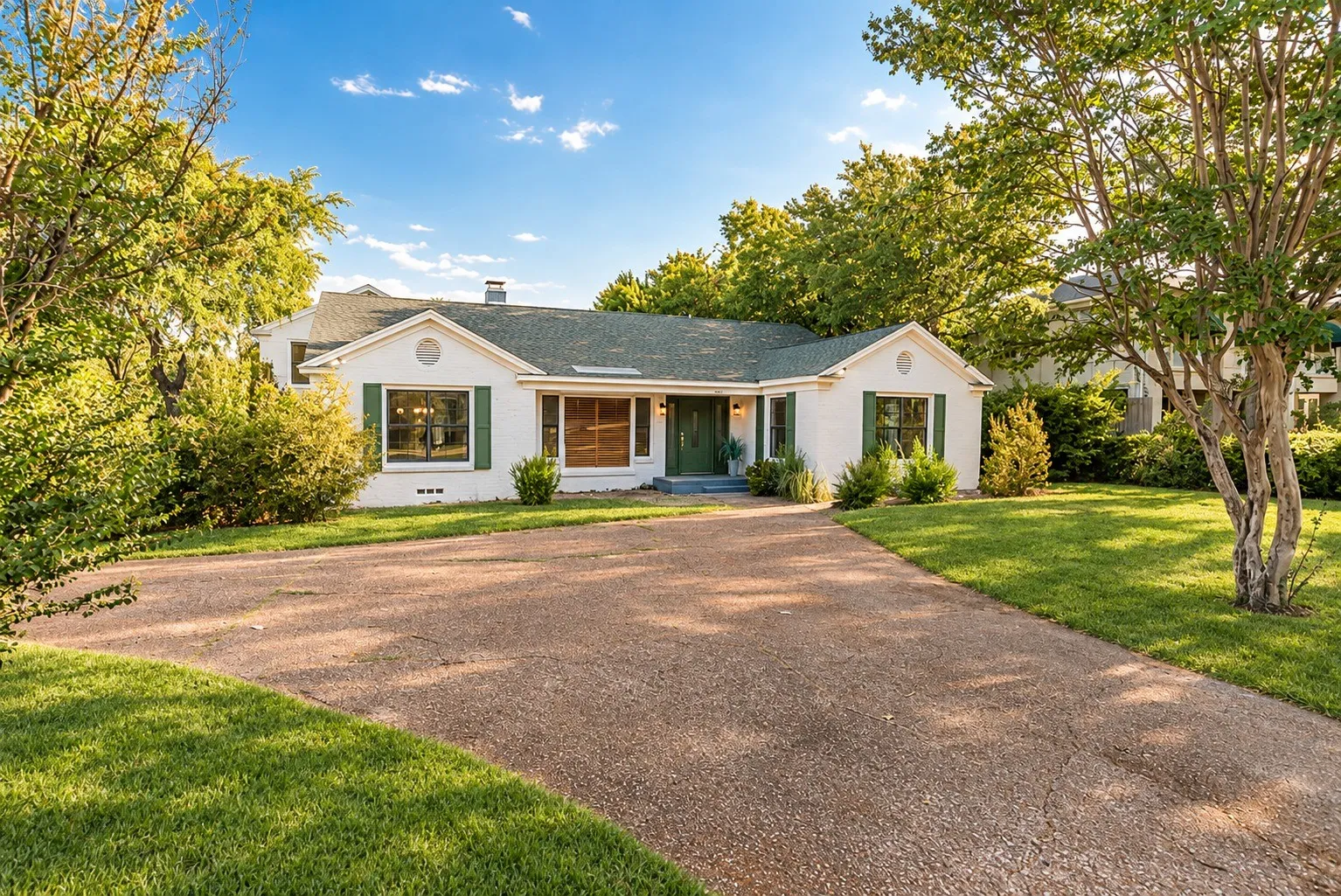 Front exterior with circular drive, green lawn and mature trees