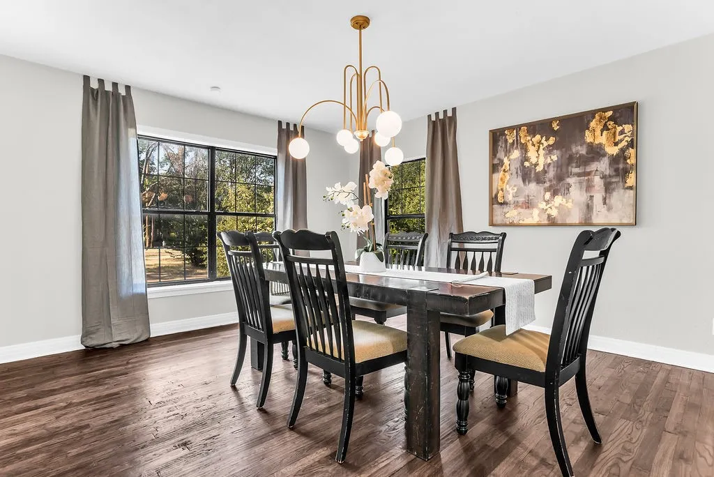 Formal dining room with large windows and modern chandelier