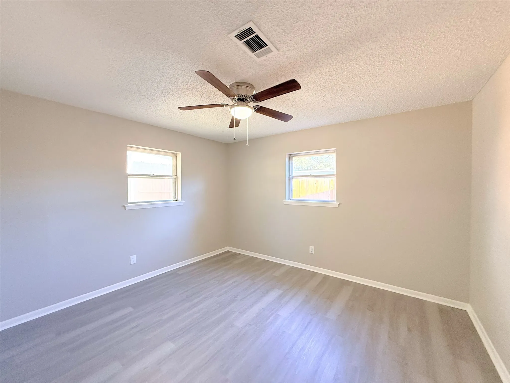 Recessed lighting, wood-finish flooring, two windows, and a ceiling fan with integrated lighting