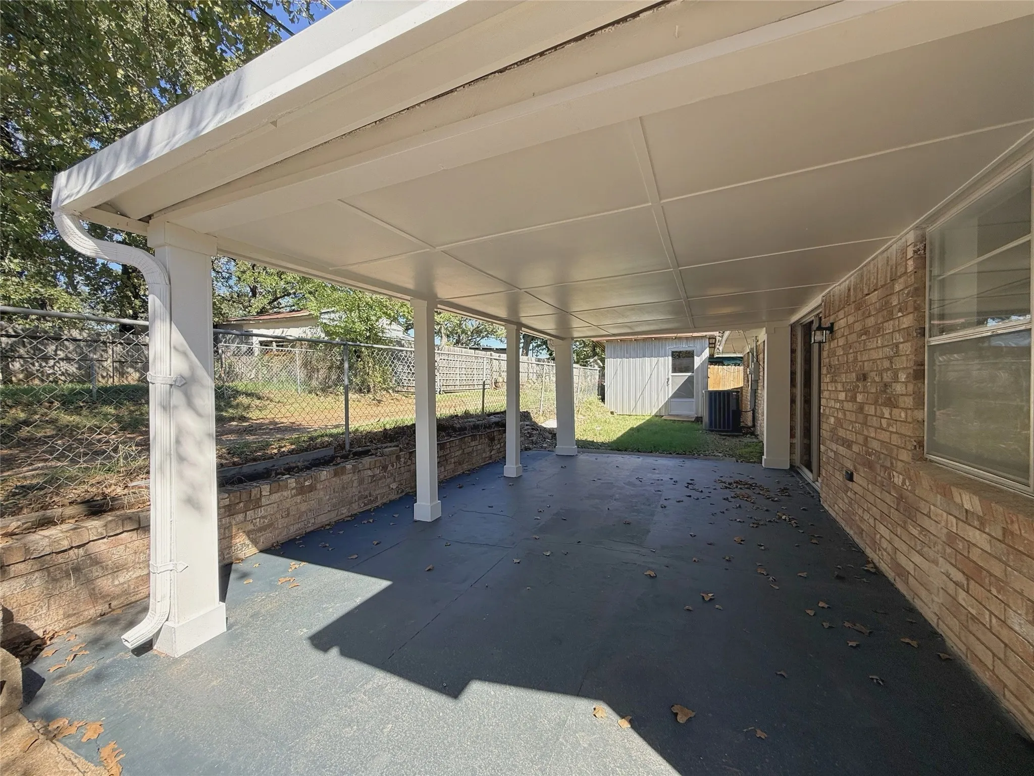 Expansive covered patio with a textured concrete surface and white support columns