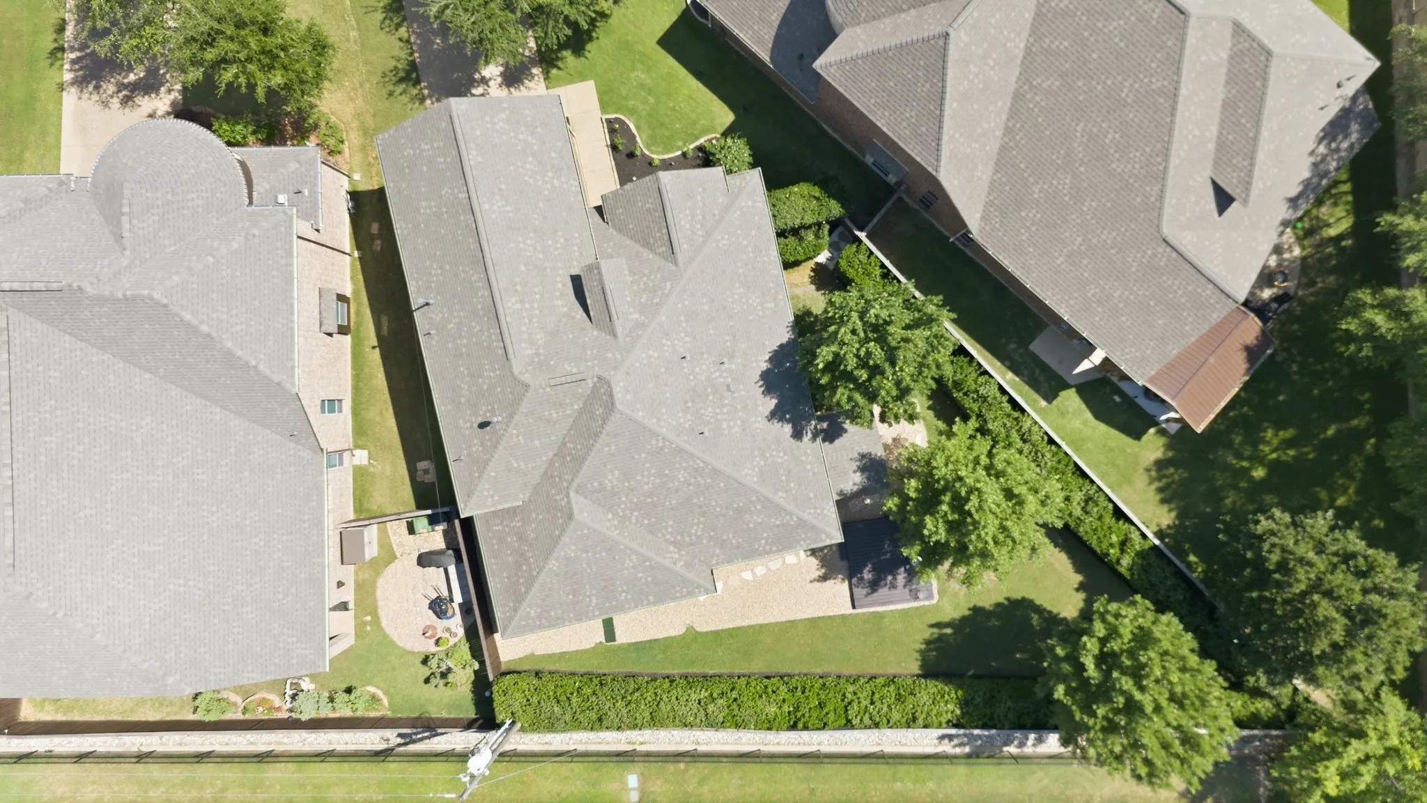 Class 4 shingle roofing, paved patio area, mature trees, manicured lawn, and perimeter hedge