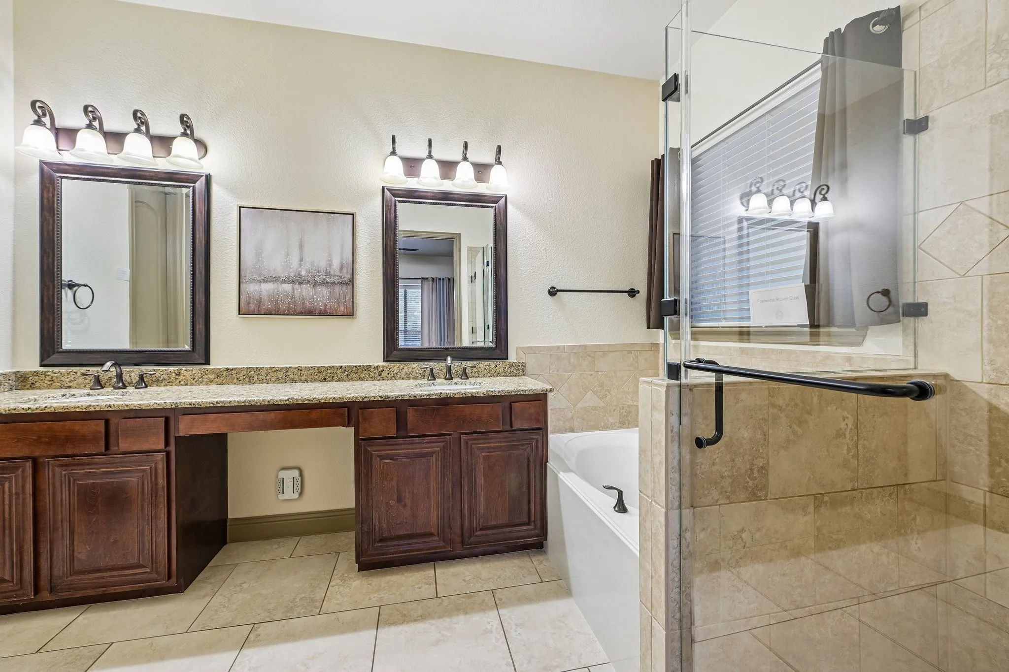 Dual sink vanity with granite-look countertop and wood-finish cabinetry. Frameless Glass Shower