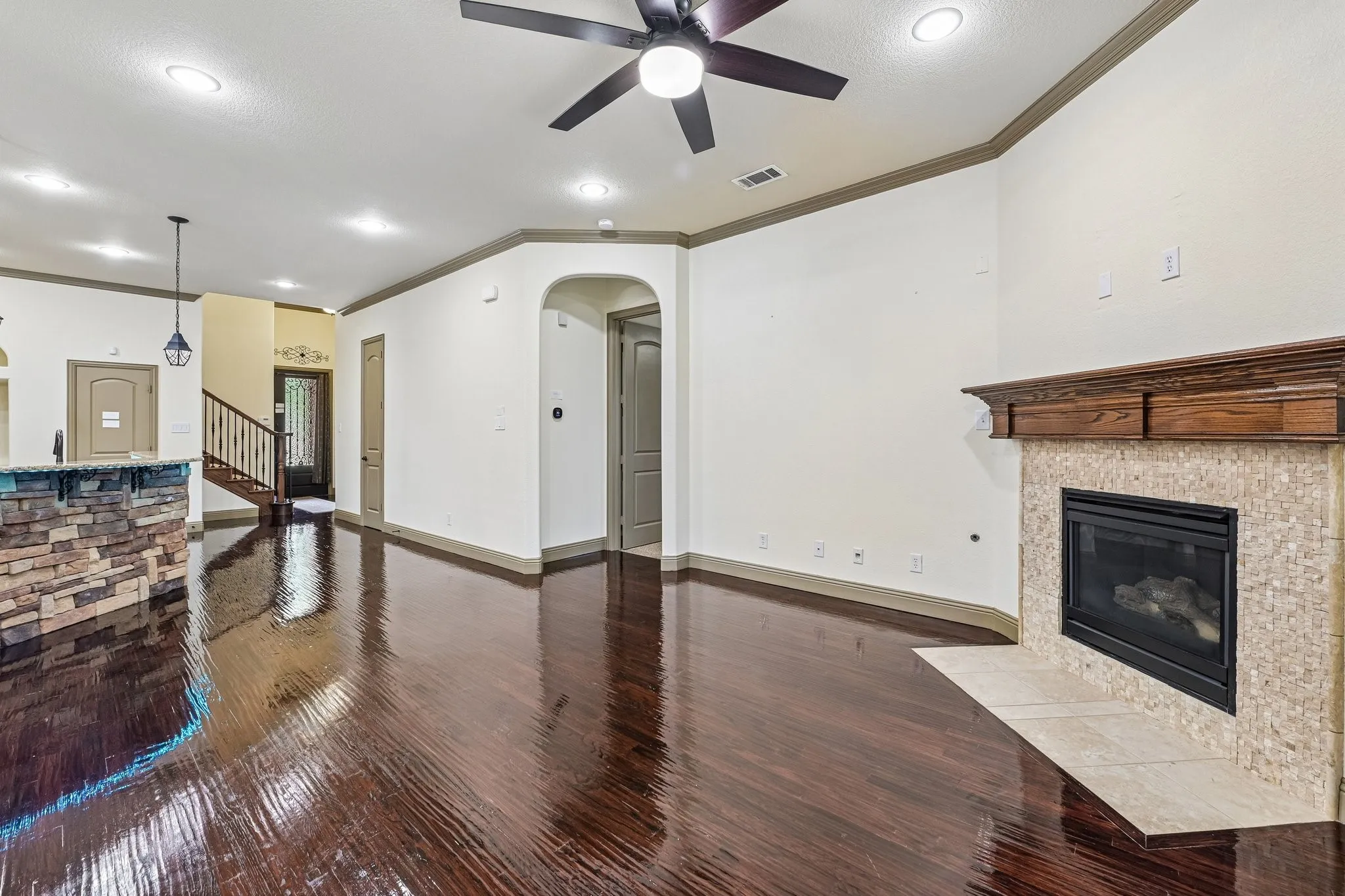 Spacious open-concept living area featuring rich wood-finish flooring throughout, recessed ceiling lighting, and a ceiling fan