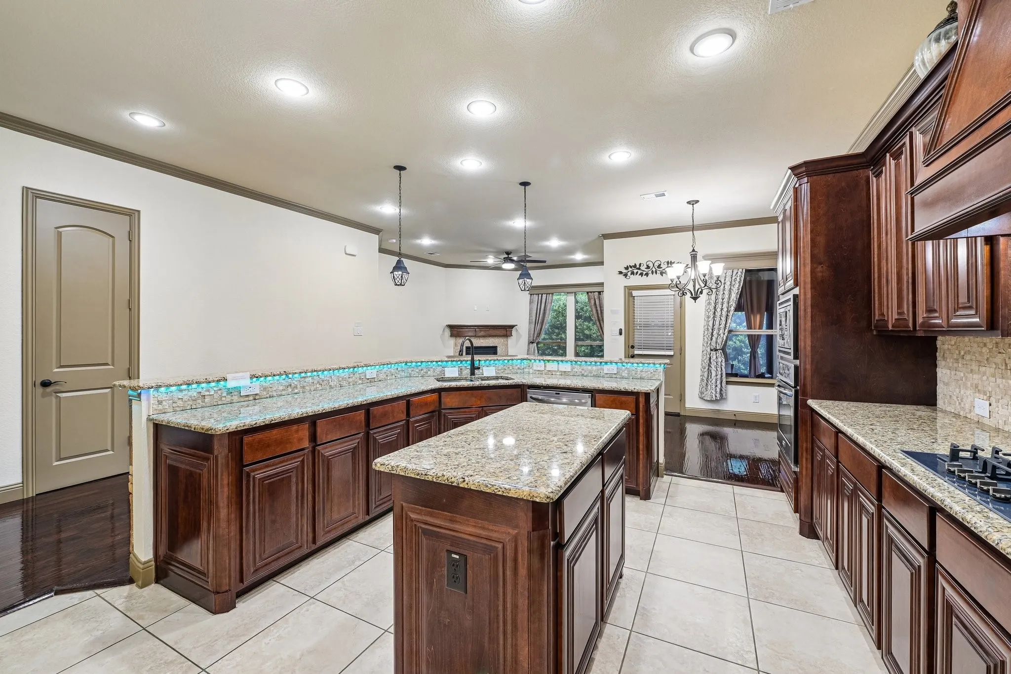 Expansive kitchen featuring a central island, rich wood cabinetry, light granite countertops, and tile flooring