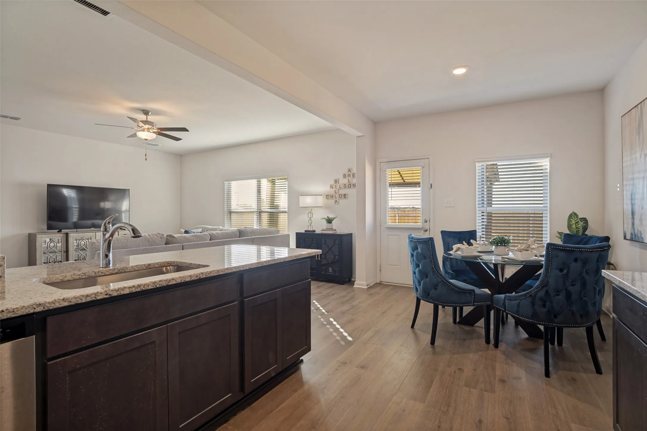 Spacious kitchen island with an undermount sink, wood-finish flooring, recessed lighting, and a ceiling fan