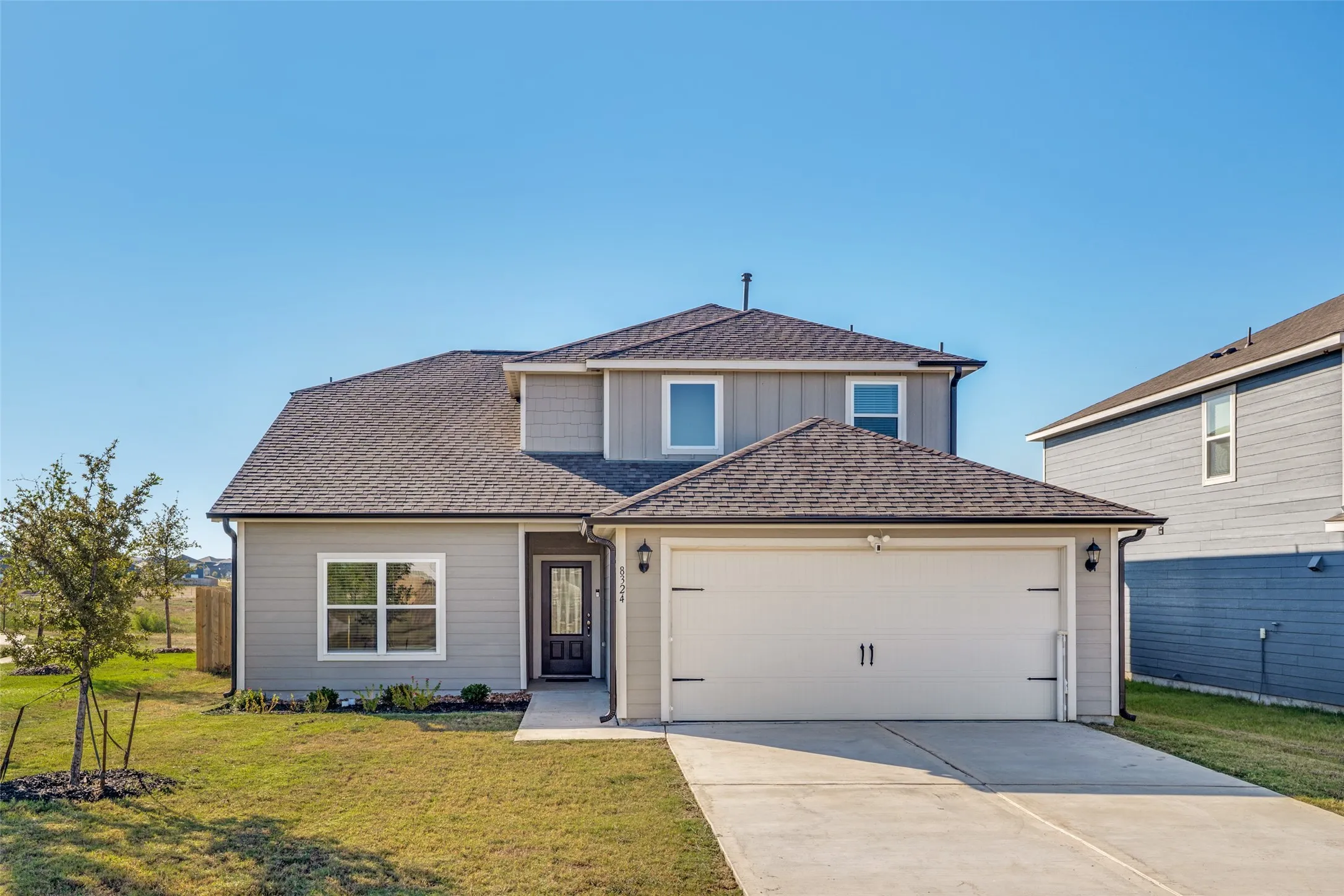 Contemporary two-story residence with gray siding, a two-car garage, and a dark front door with glass inserts