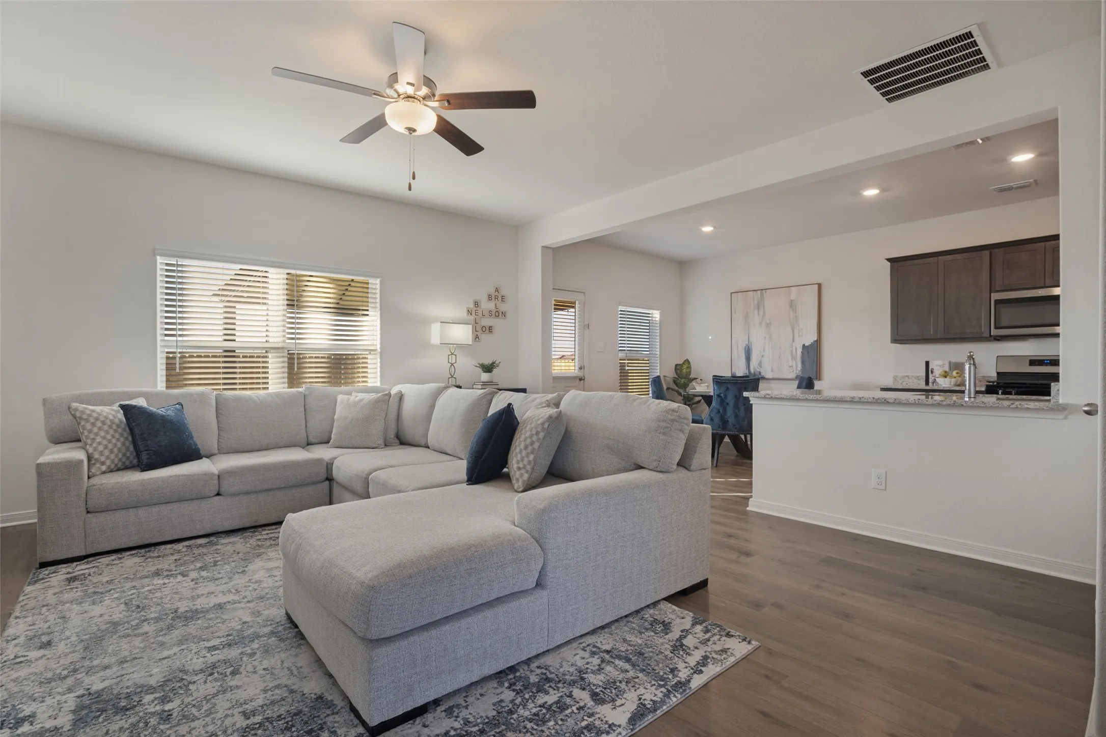 Open-concept living area featuring wood-finish flooring, recessed lighting, a ceiling fan, and a kitchen pass-through with a countertop