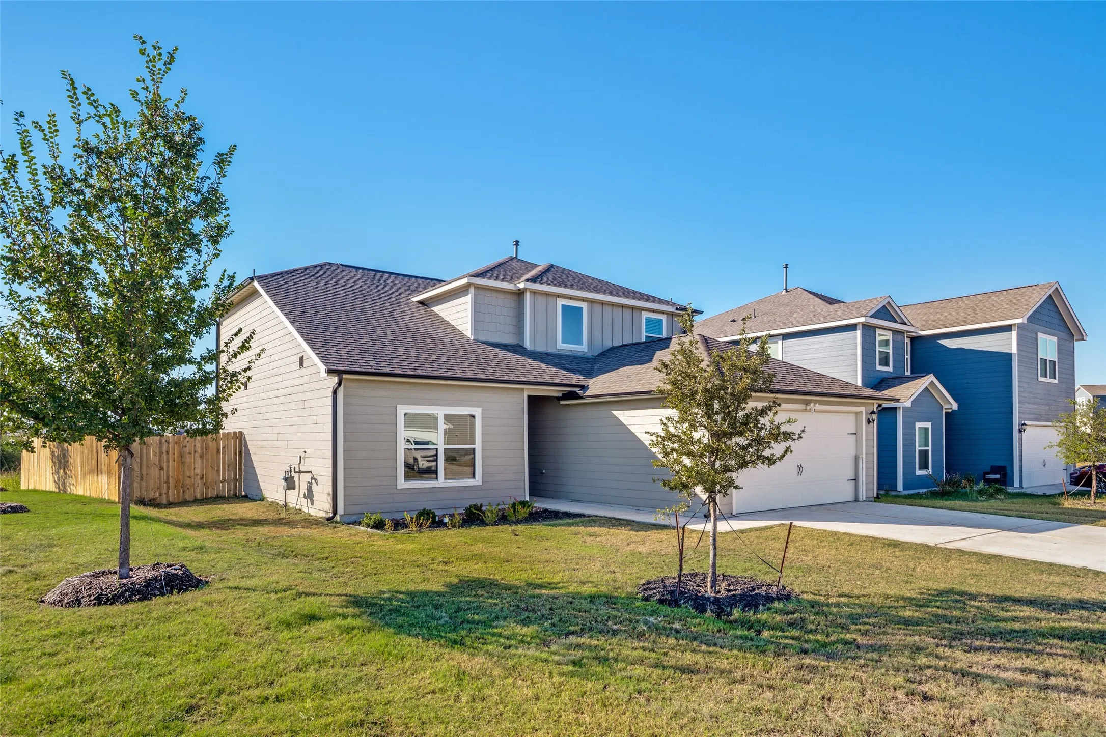 Two-story residence featuring a light-colored exterior with architectural accents, gabled roofline with dimensional shingles, and a three-car garage
