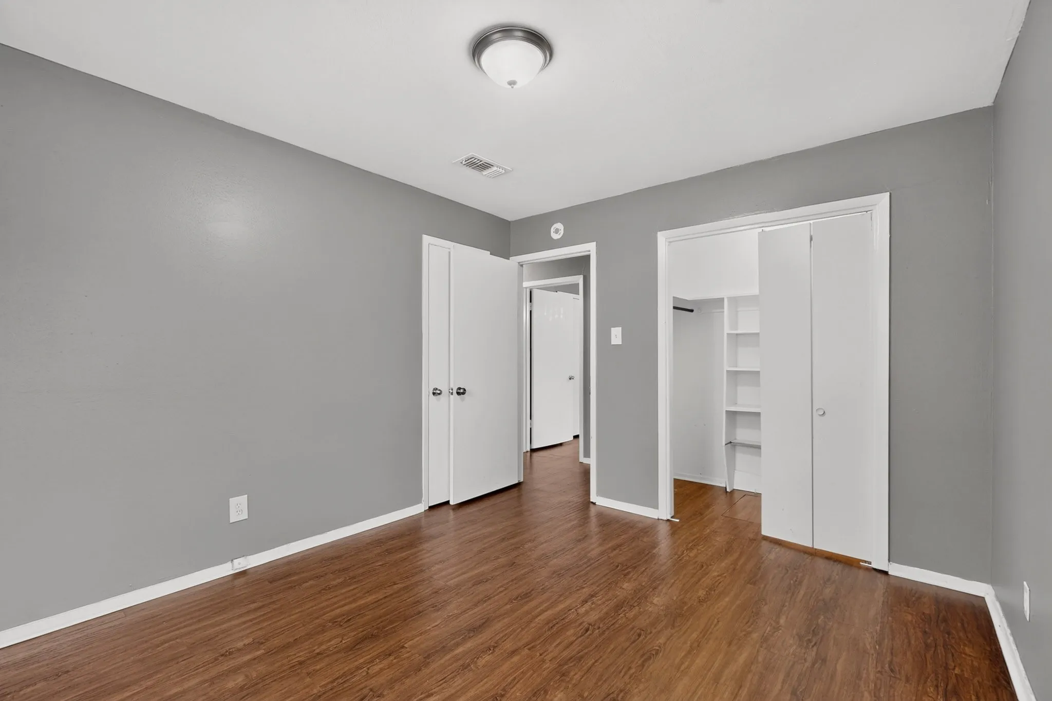 Wood-finish flooring, neutral gray walls, and white trim throughout