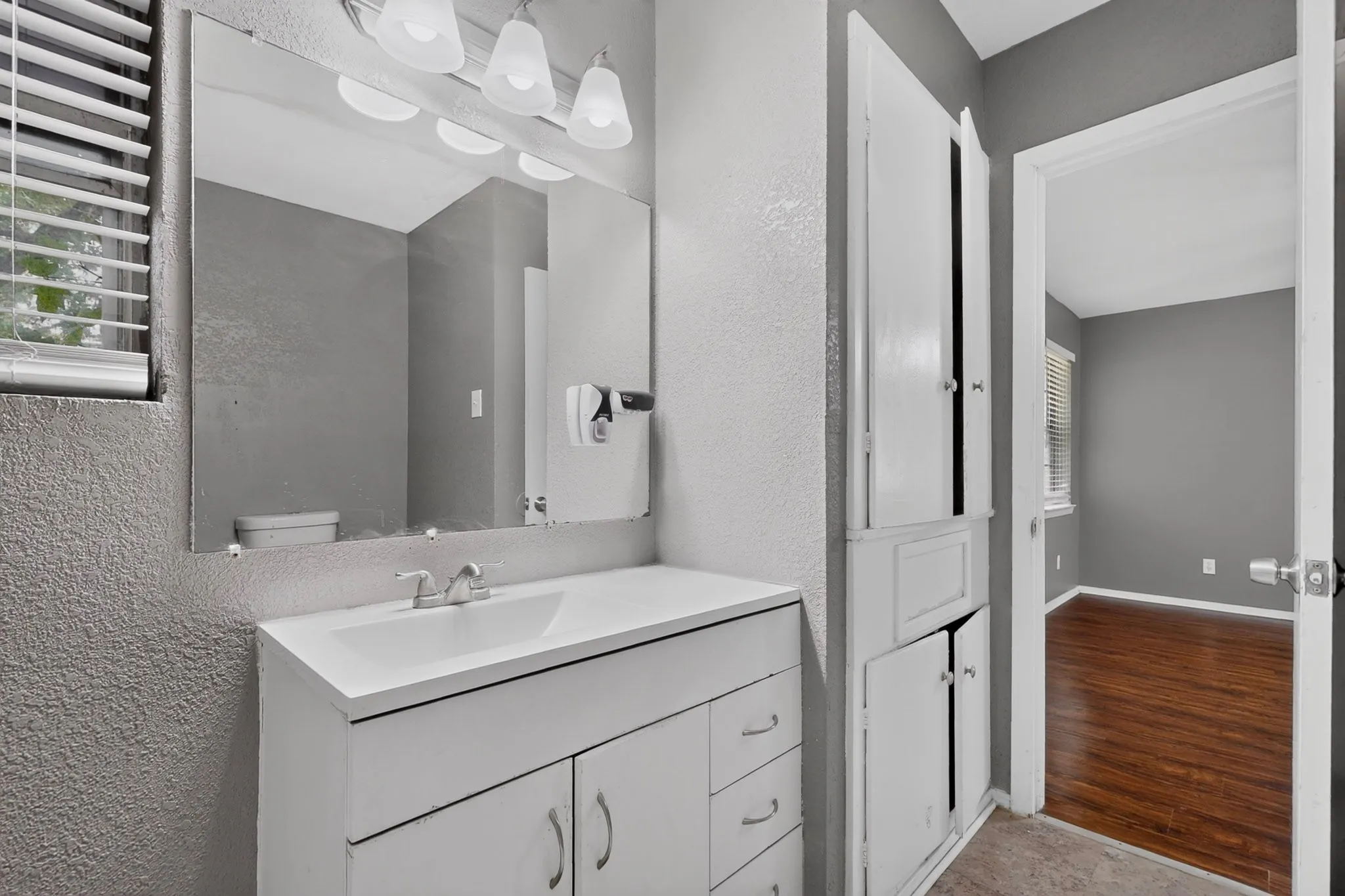 Vanity with integrated sink, wall-mounted mirror, and overhead light fixture