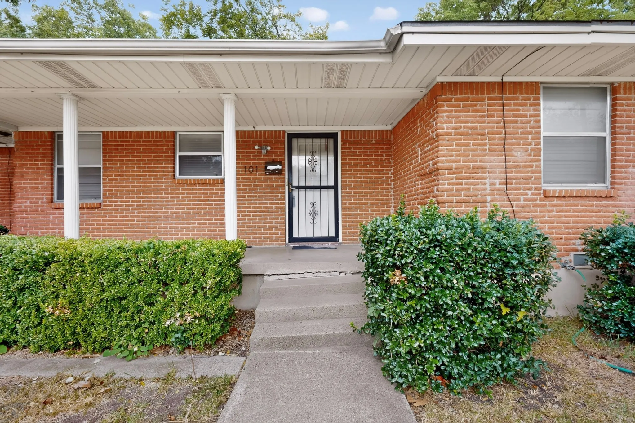 Brick exterior with covered front entry and concrete walkway