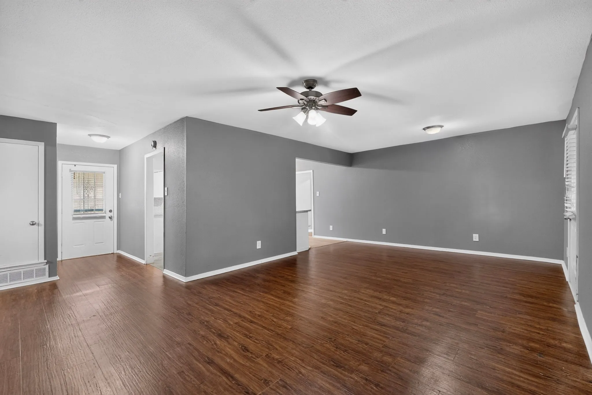Wood-finish flooring throughout, ceiling fan with integrated lighting, recessed lighting, and a white paneled door with glass inserts