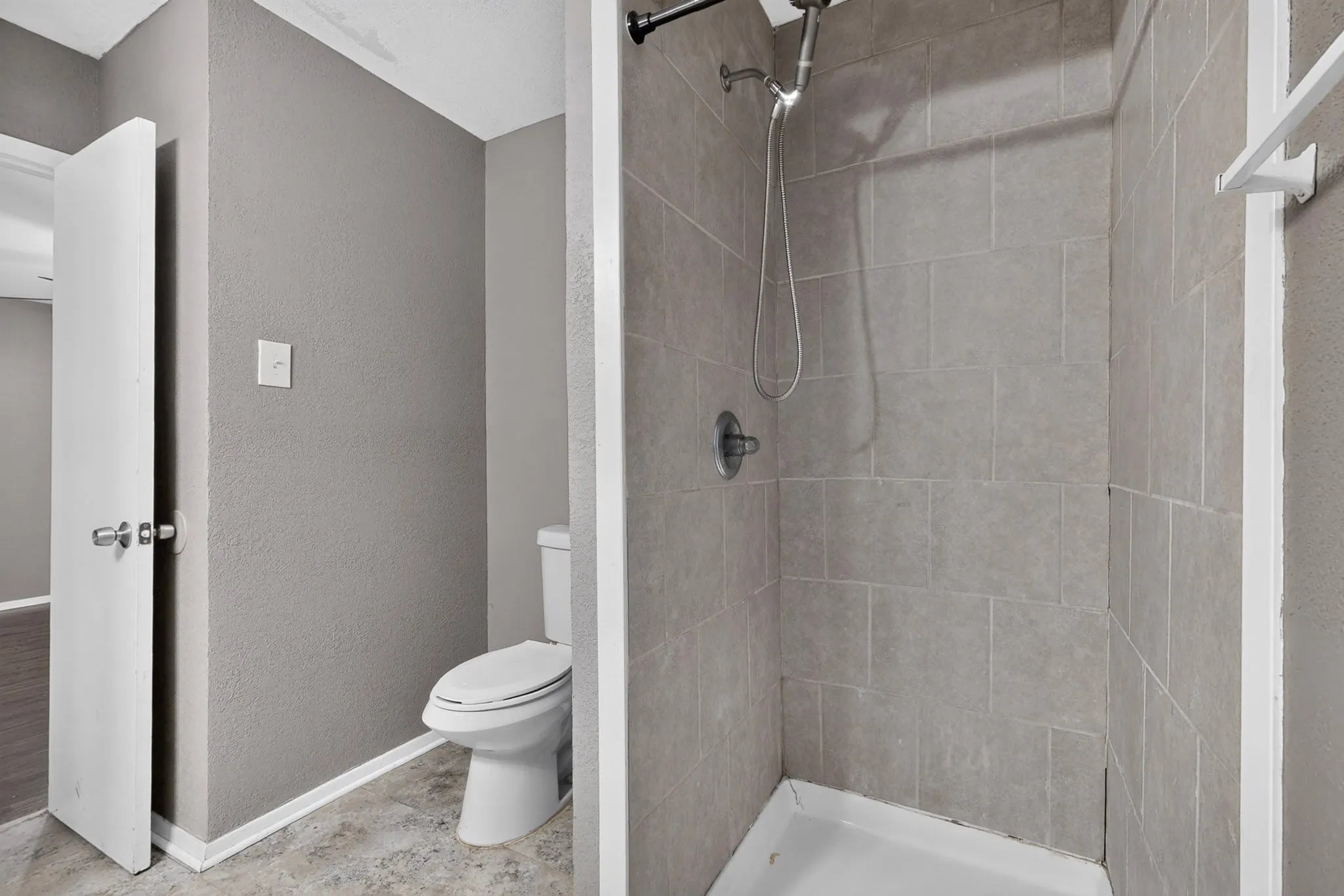 Tiled shower stall with a white base and a chrome shower head