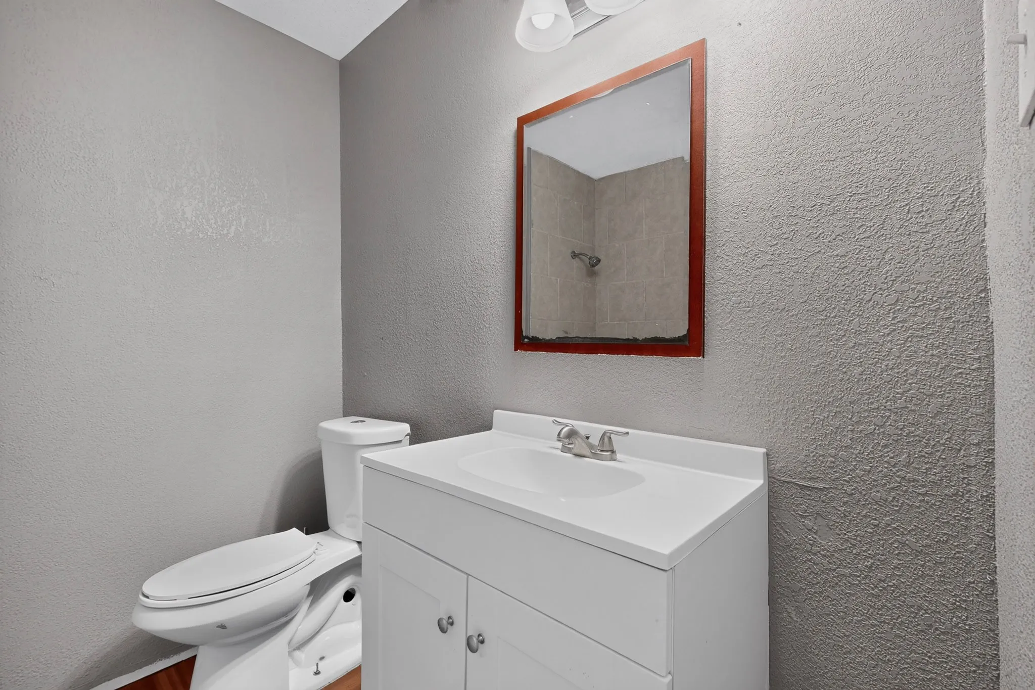 Bathroom featuring a single vanity with storage, a wall-mounted mirror, and a toilet