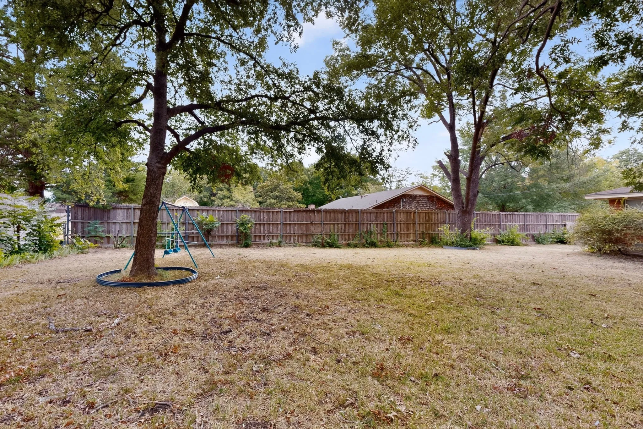 Expansive backyard with a full privacy fence and mature trees