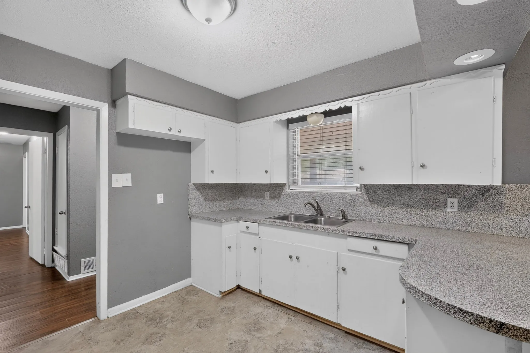Kitchen featuring white cabinetry, a double basin stainless steel sink, speckled countertops, and ceiling-mounted lighting